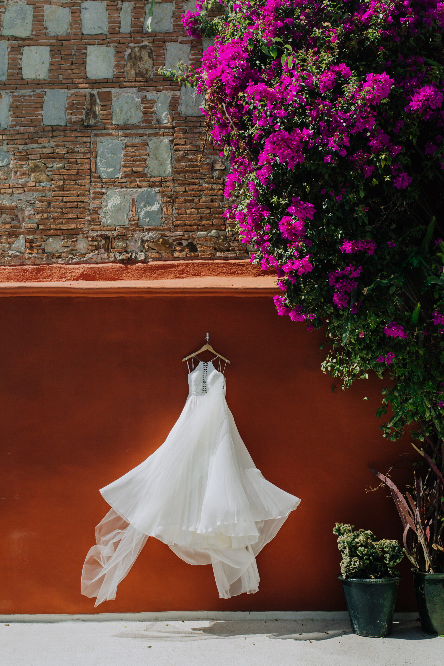 brides dress hangs up against an orange wall 