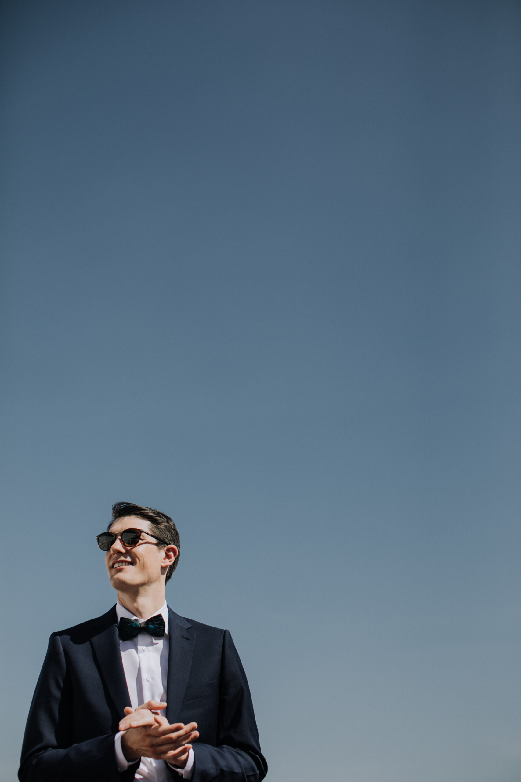 groom stands against a perfect blue Mexico sky