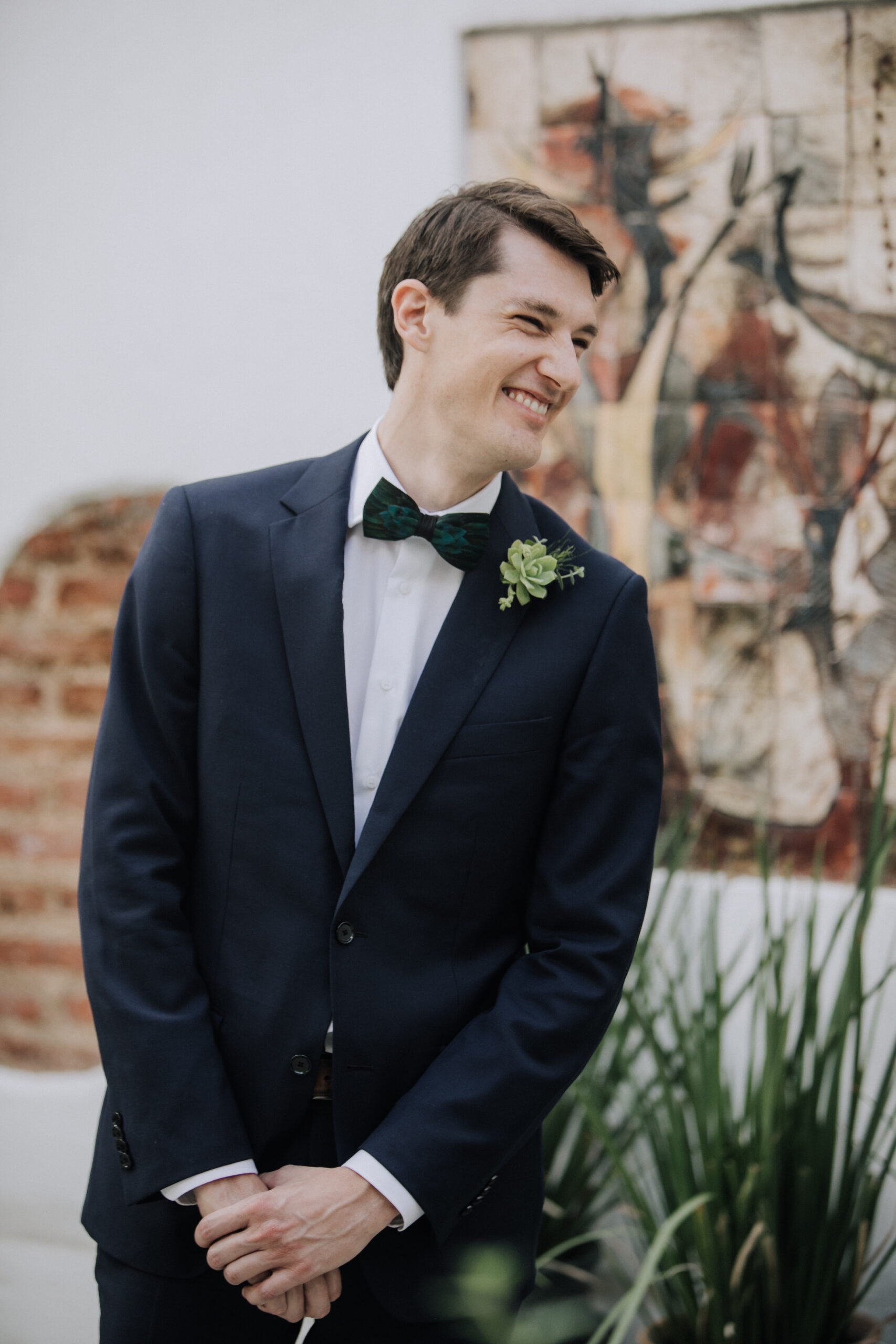groom patiently awaits his bride at their first look photoshoot