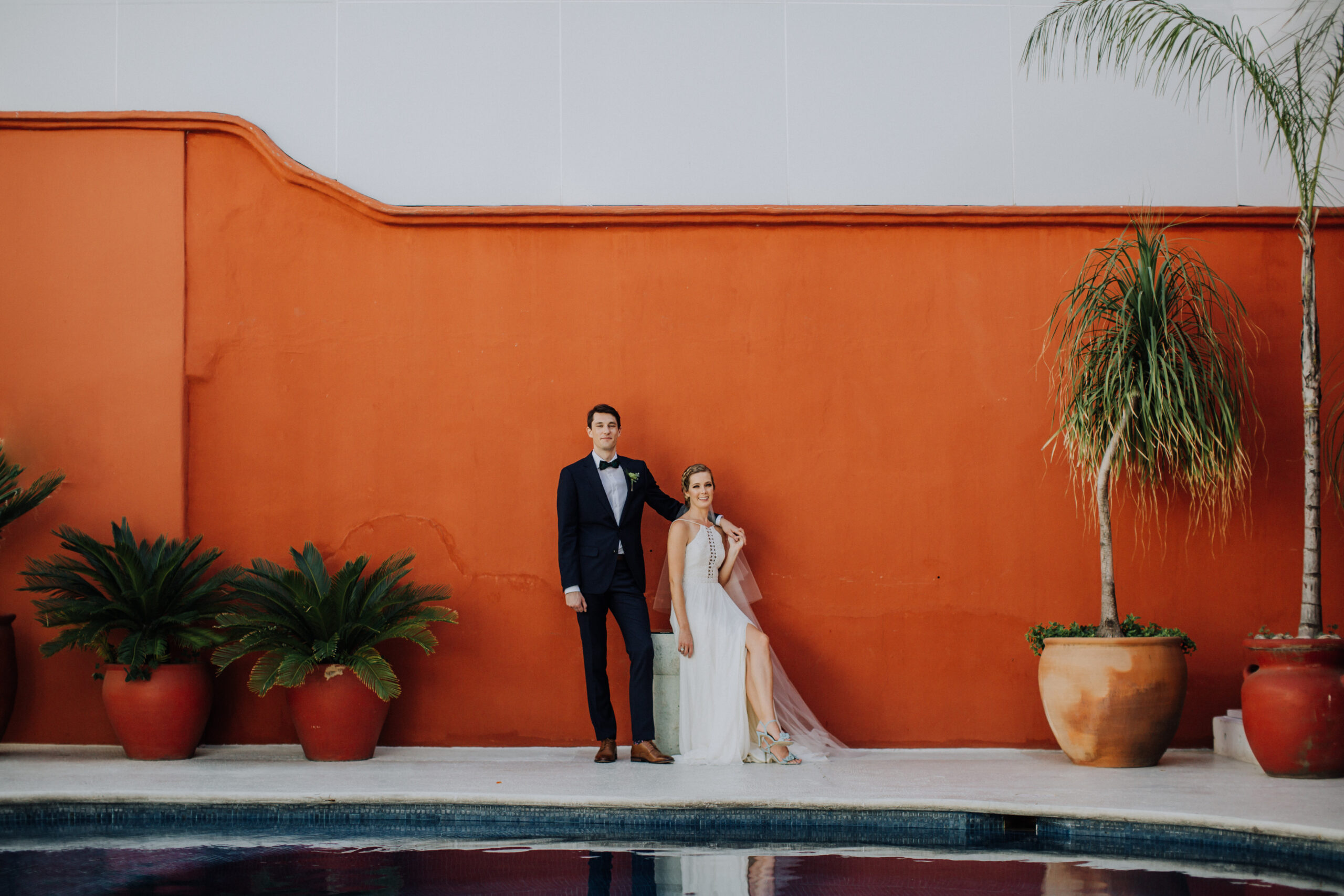bride and groom pose against a stunning orange wall