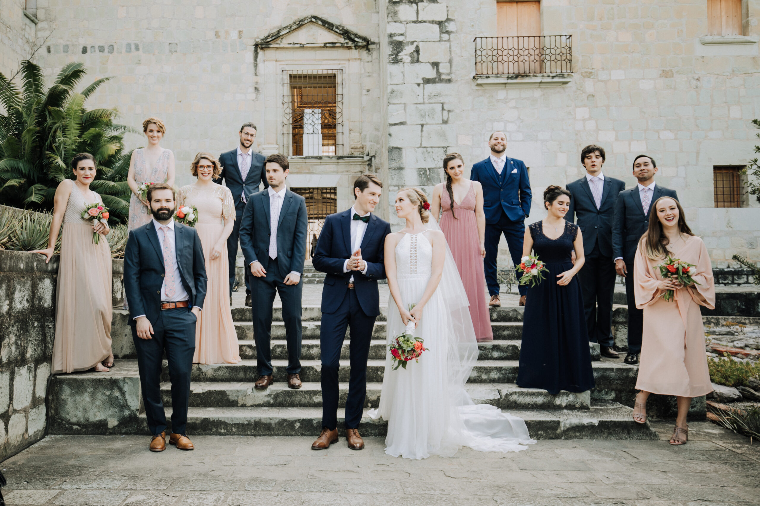 Stunning bride and groom pose with their wedding party in front of a stunning church after their stunning Oaxaca Wedding 