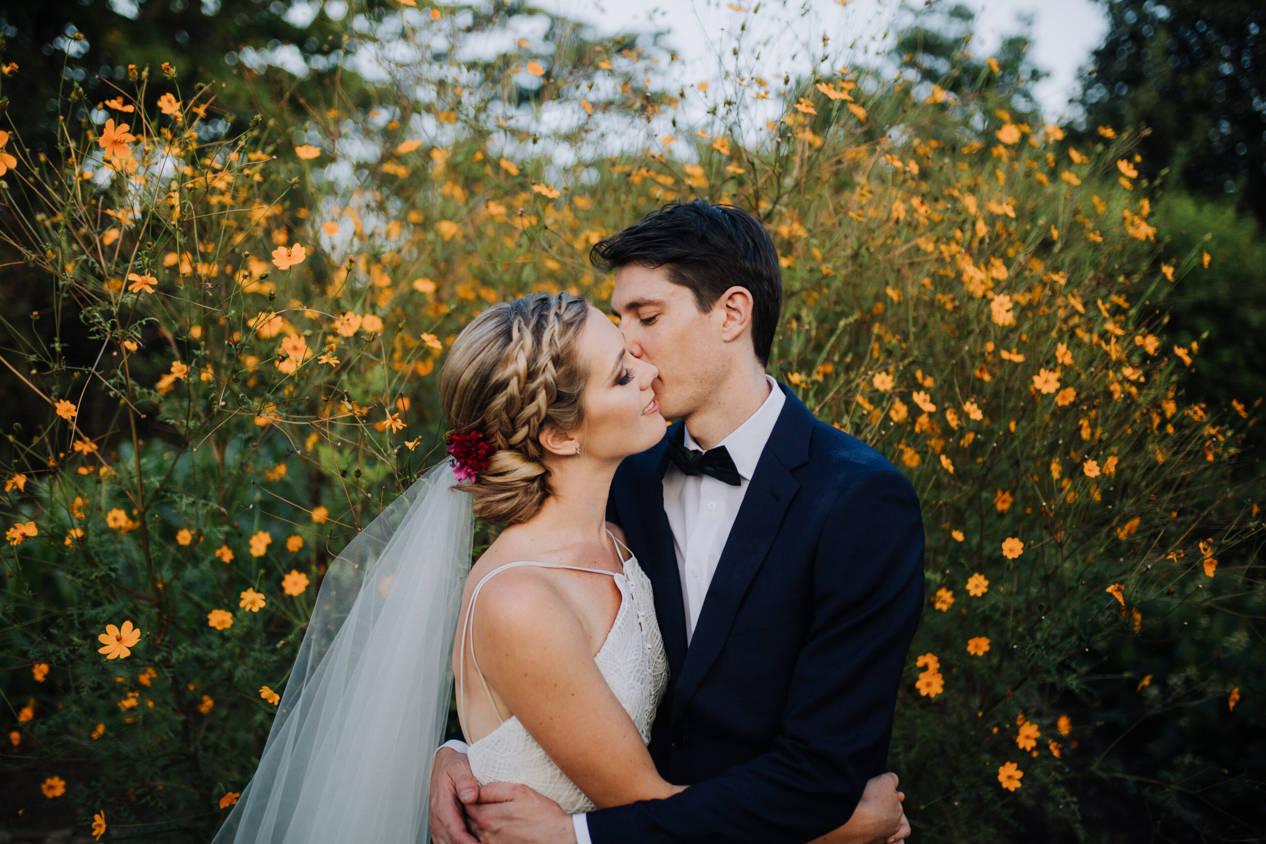 beautiful bride and groom pose in front of stunning yellow wildflowers