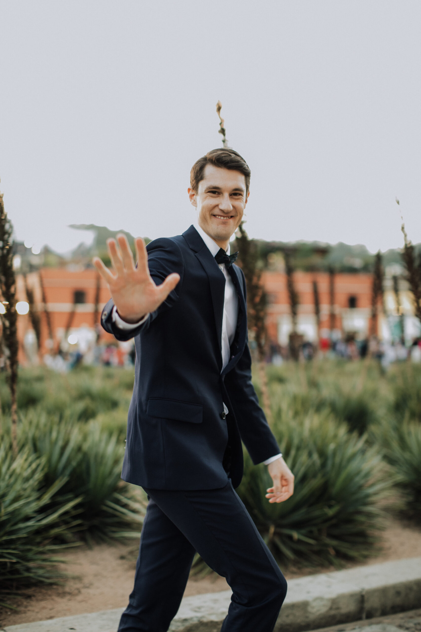 groom waves hello at the camera as he walks by 