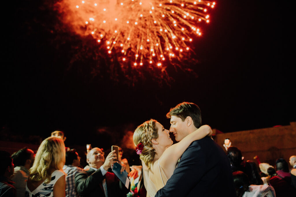 bride and groom share a kiss under the fireworks