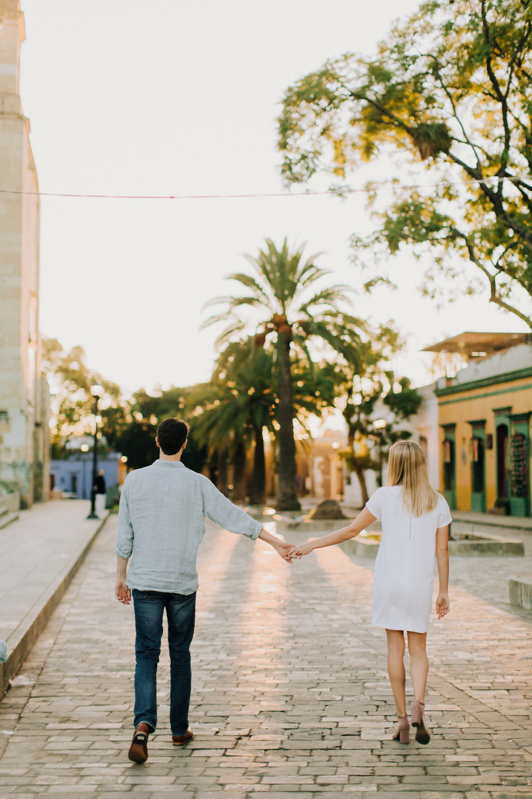 beautiful couple walk together in Oaxaca with the dreamy palm trees in the background