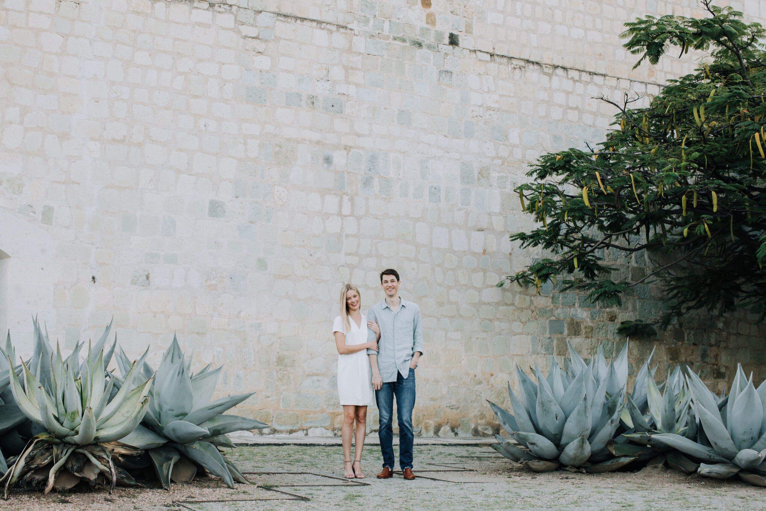 beautiful couple poses for their romantic oaxaca engagement photoshoot against a colorful back wall