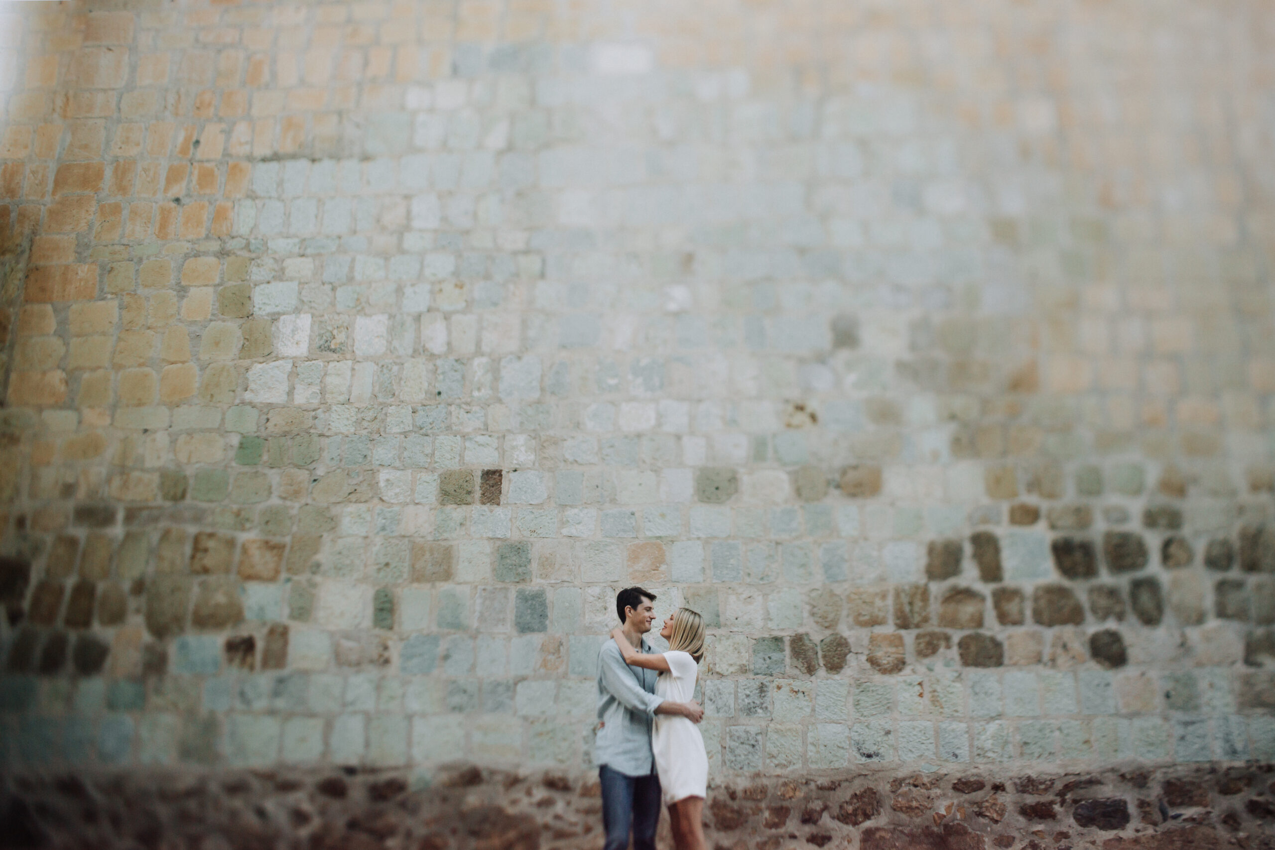 beautiful couple poses for their romantic oaxaca engagement photoshoot against a colorful back wall