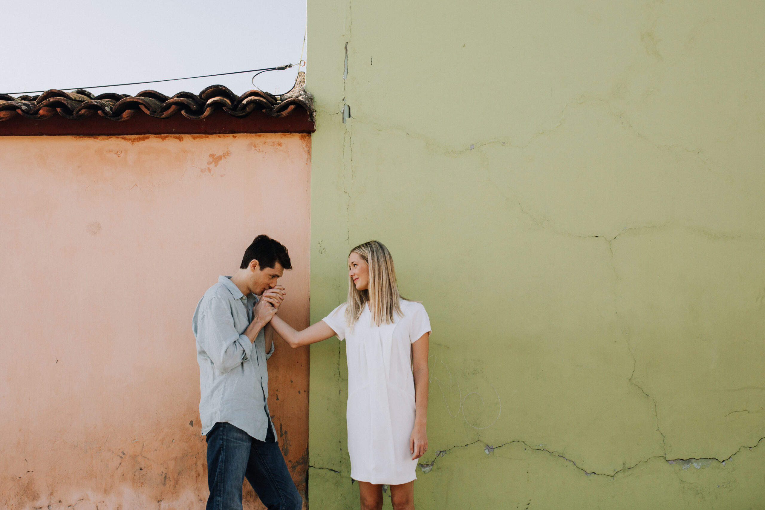 stunning bride and groom pose against a green and orange wall during their dreamy Oaxaca engagement photoshoot