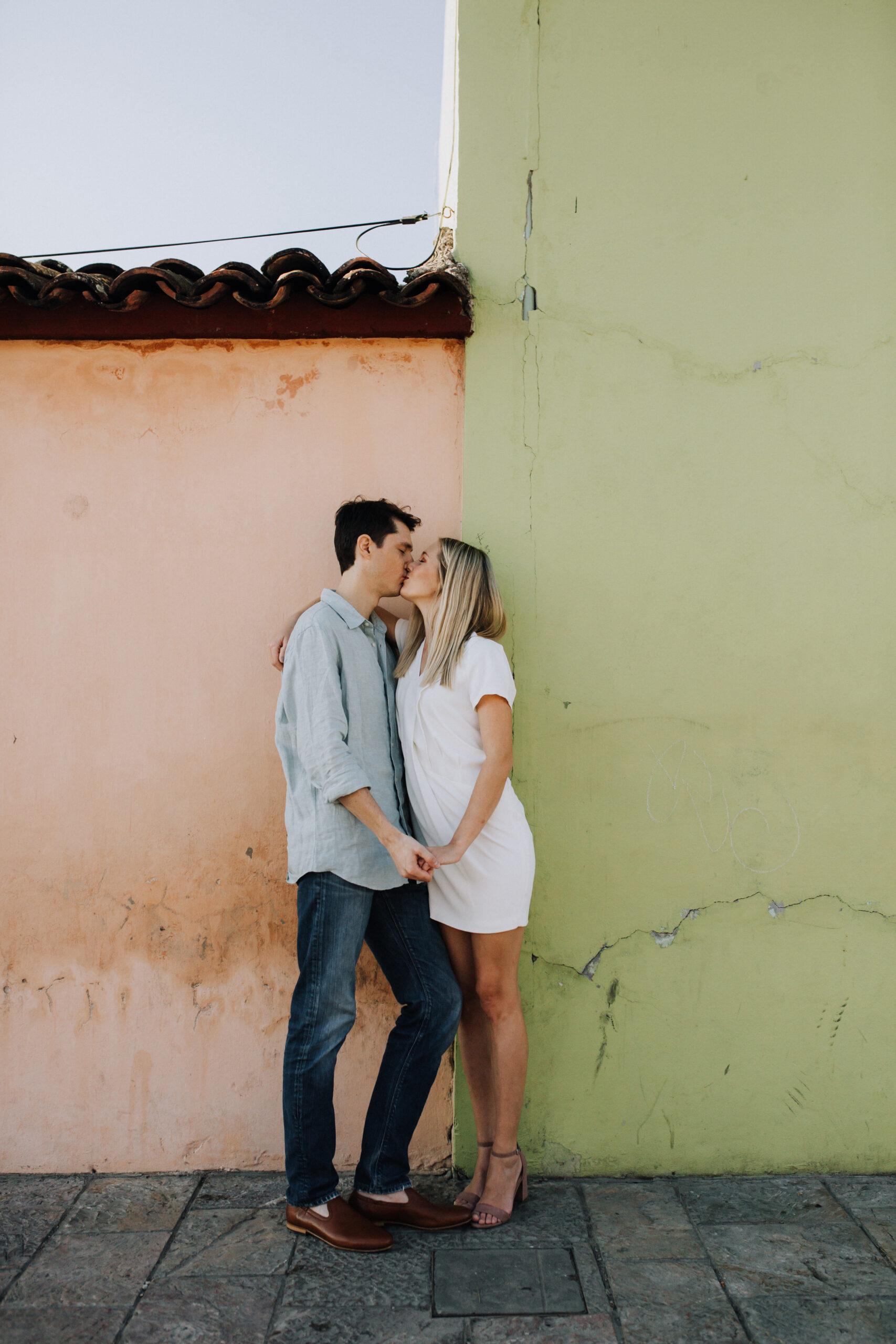 stunning bride and groom pose against a green and orange wall during their dreamy Oaxaca engagement photoshoot