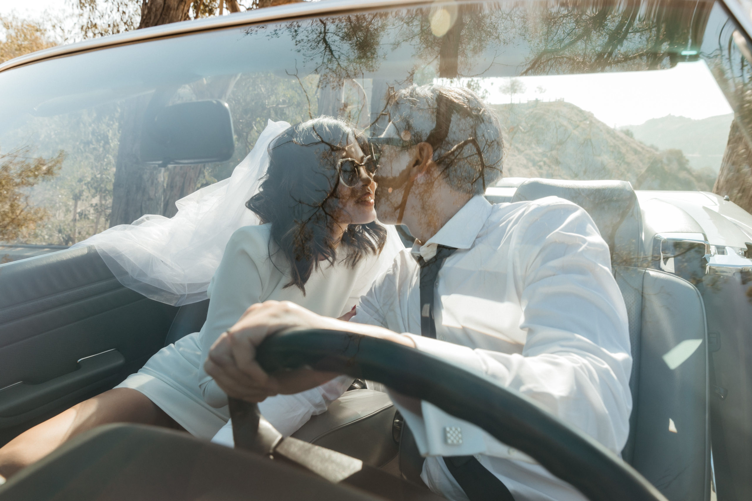 beautiful bride and groom pose in a convertible together overlooking the LA mountains 