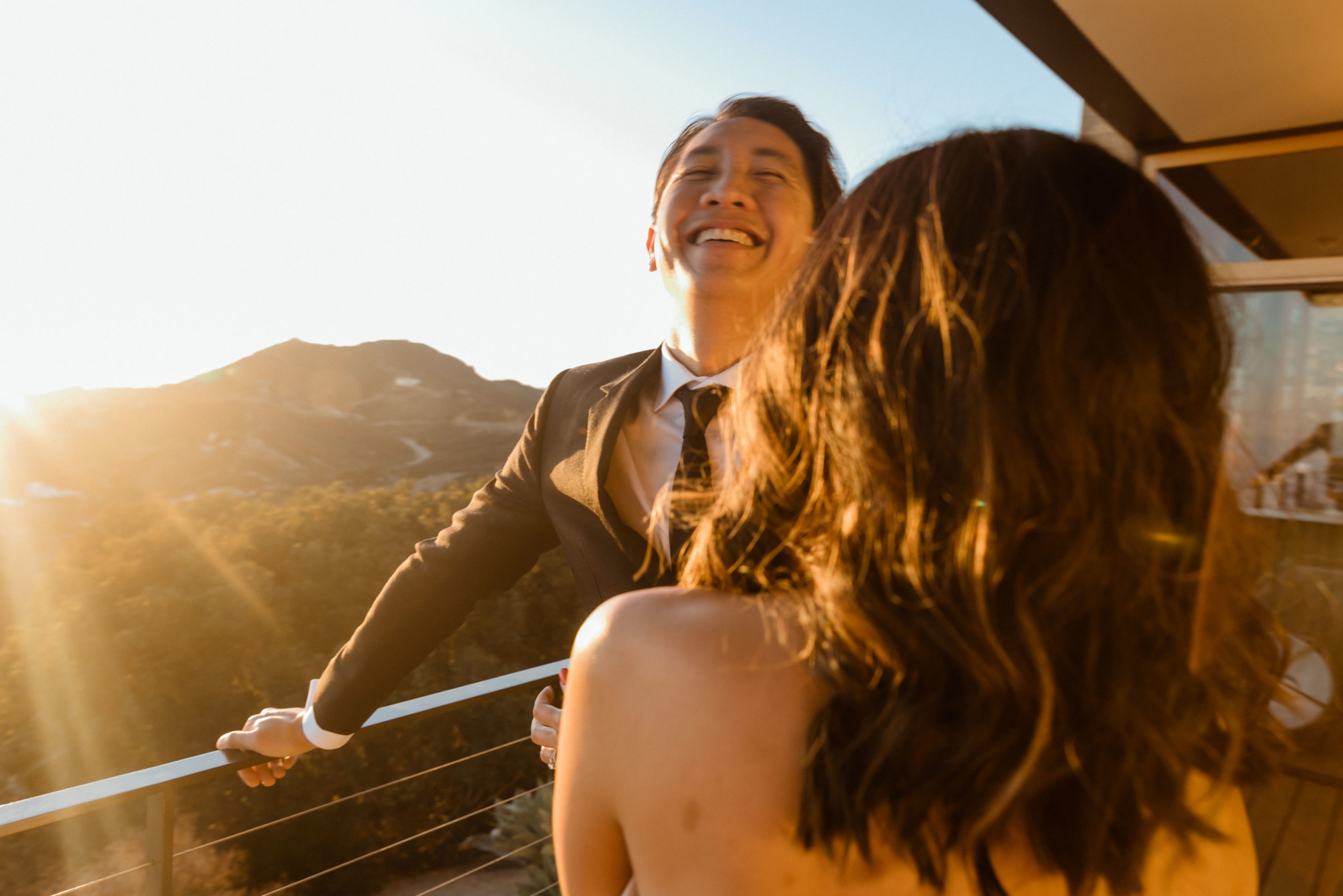 bride and groom pose together with the sunset in the background