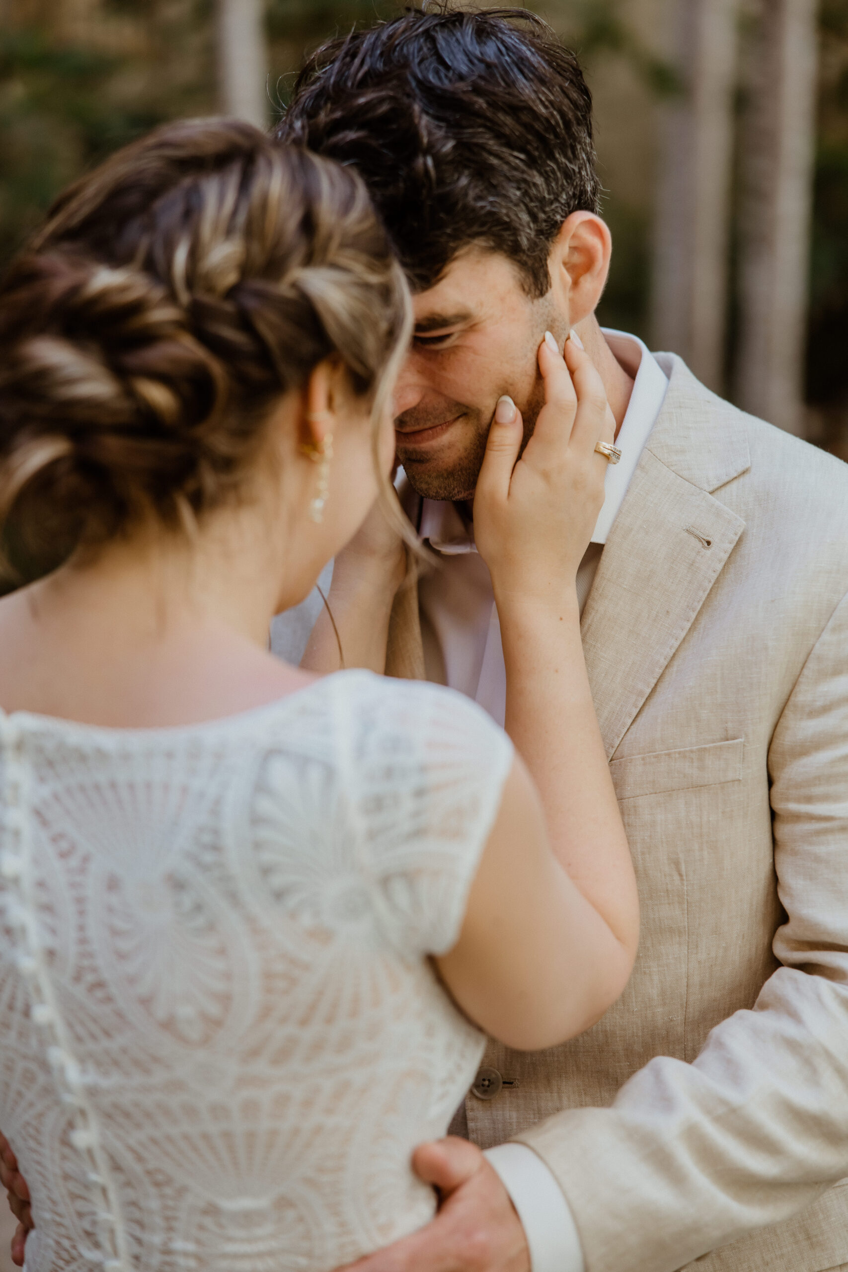 bride holding grooms face during first look.