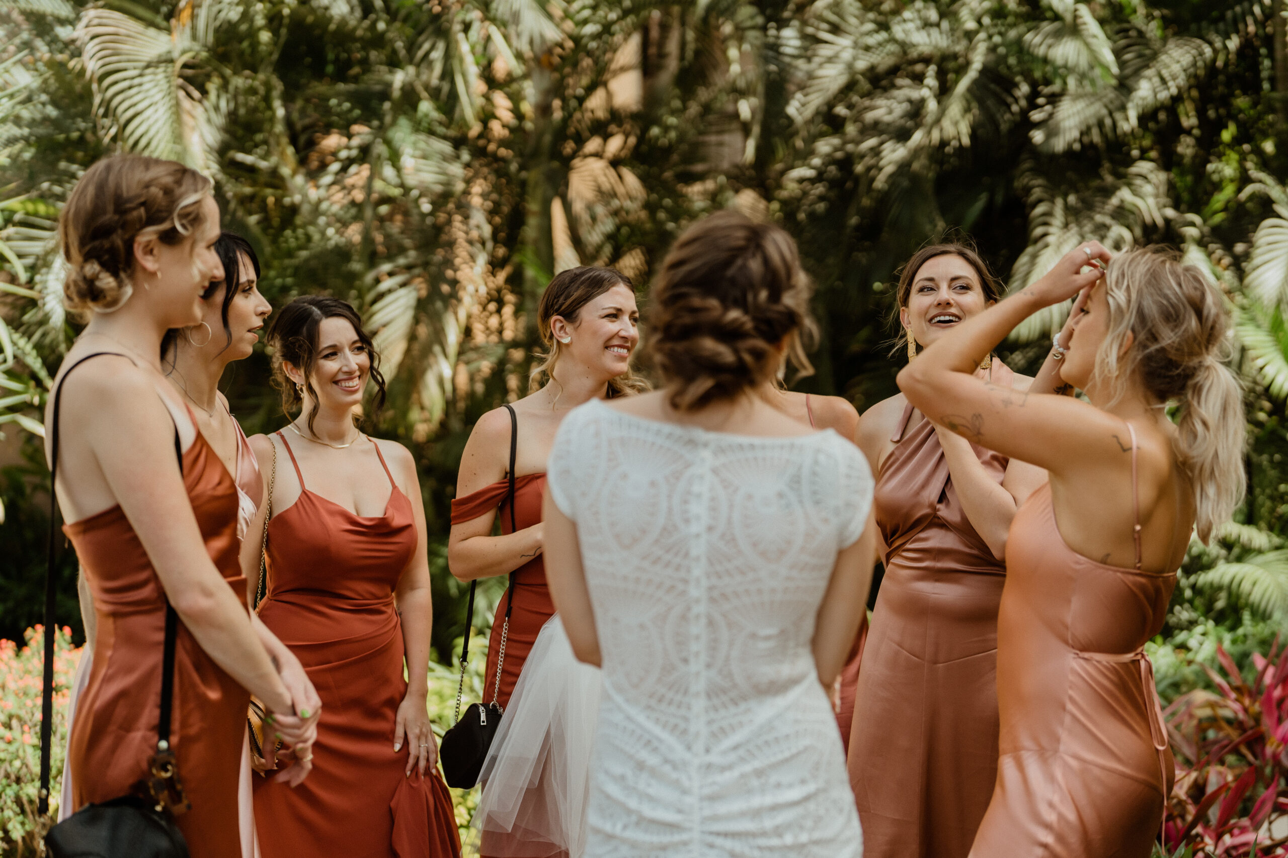 bride laughing with bridesmaids in terracotta dresses.