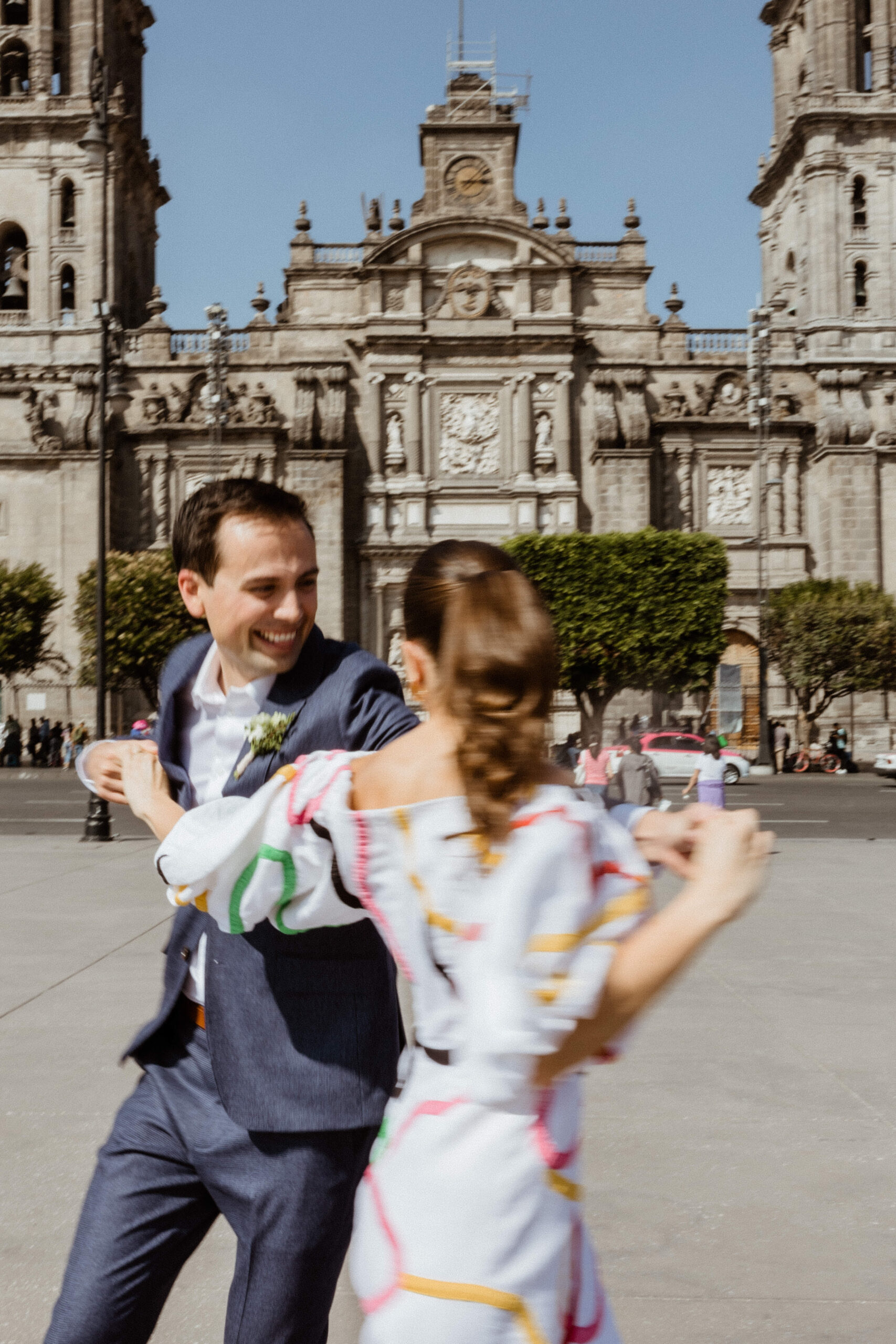 man and woman dancing in the streets of mexico city with mexico architecture in the background.