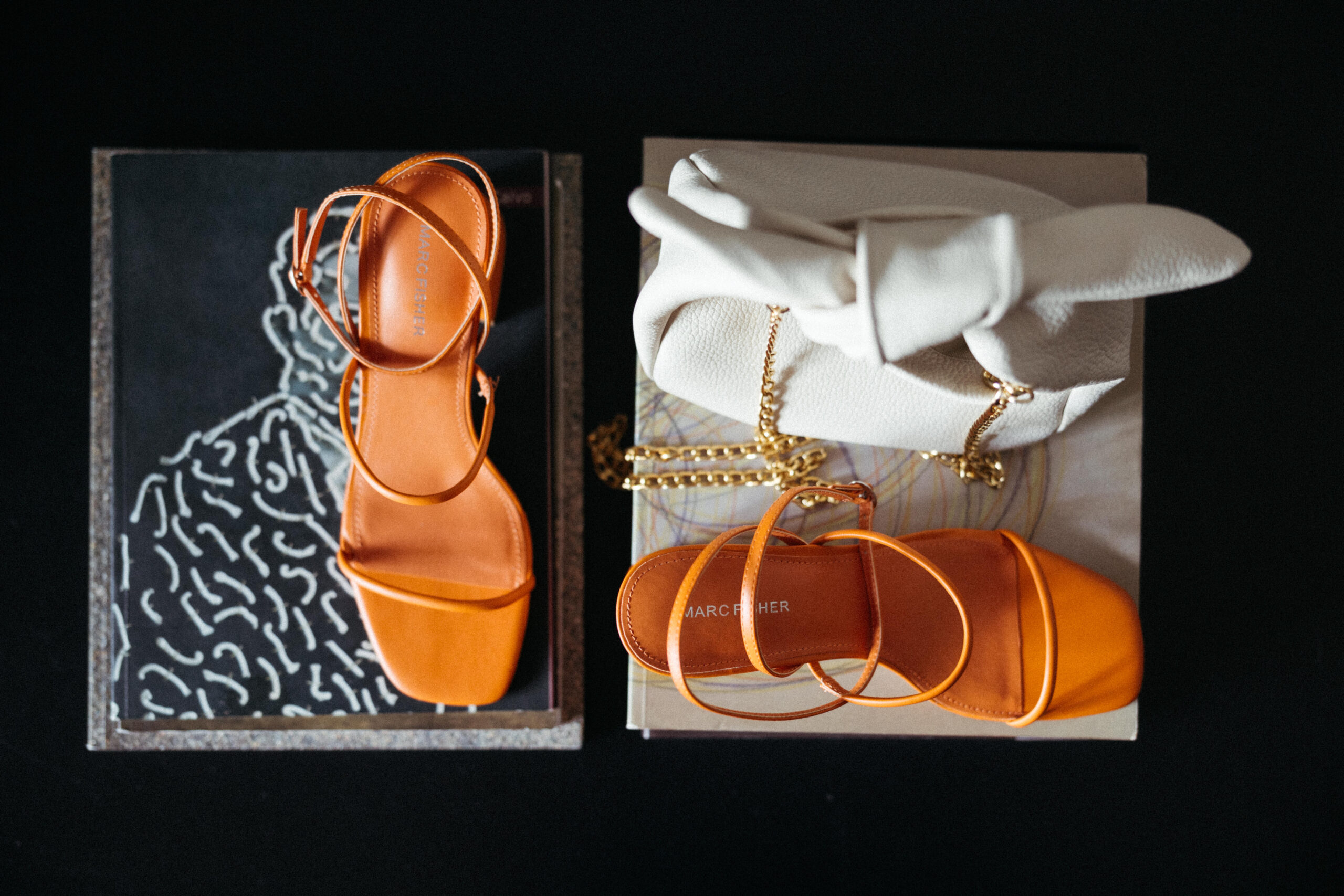 Modern bridal accessories with orange heels and gold jewelry. 