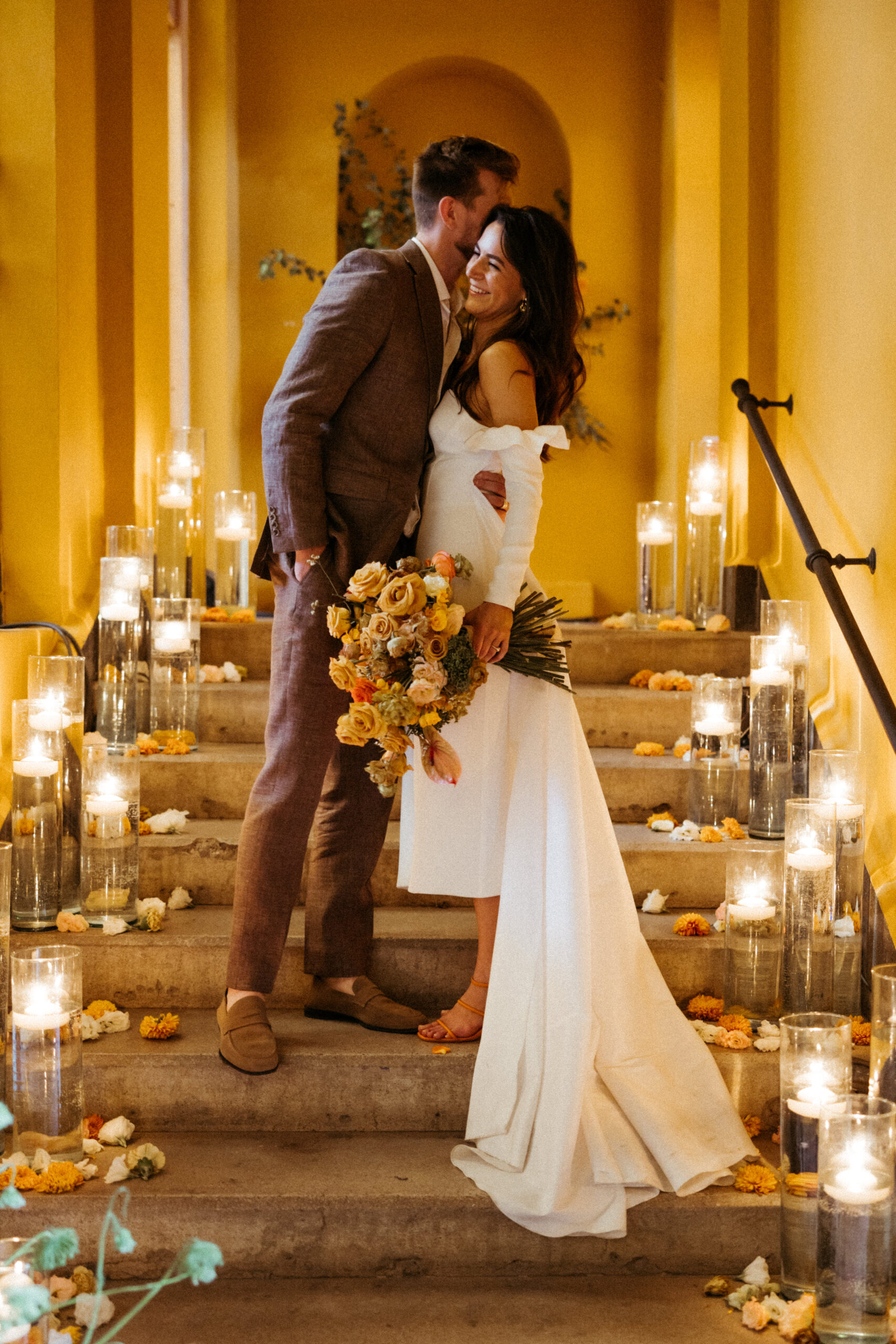 warm lighting with bride and groom hugging with candle lit stairs