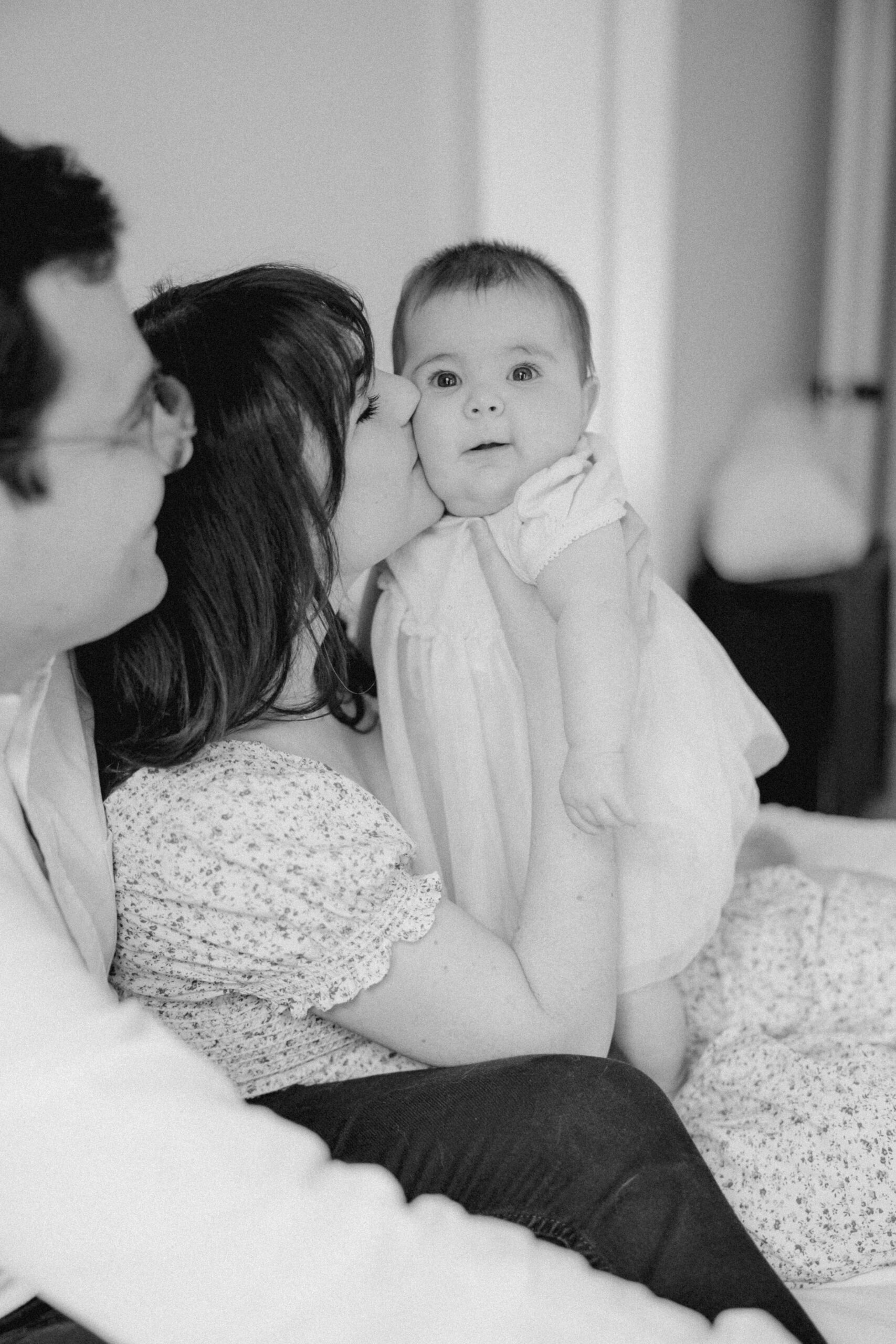 Stunning black and white photo of infant with mom and dad in their white modern baby room.