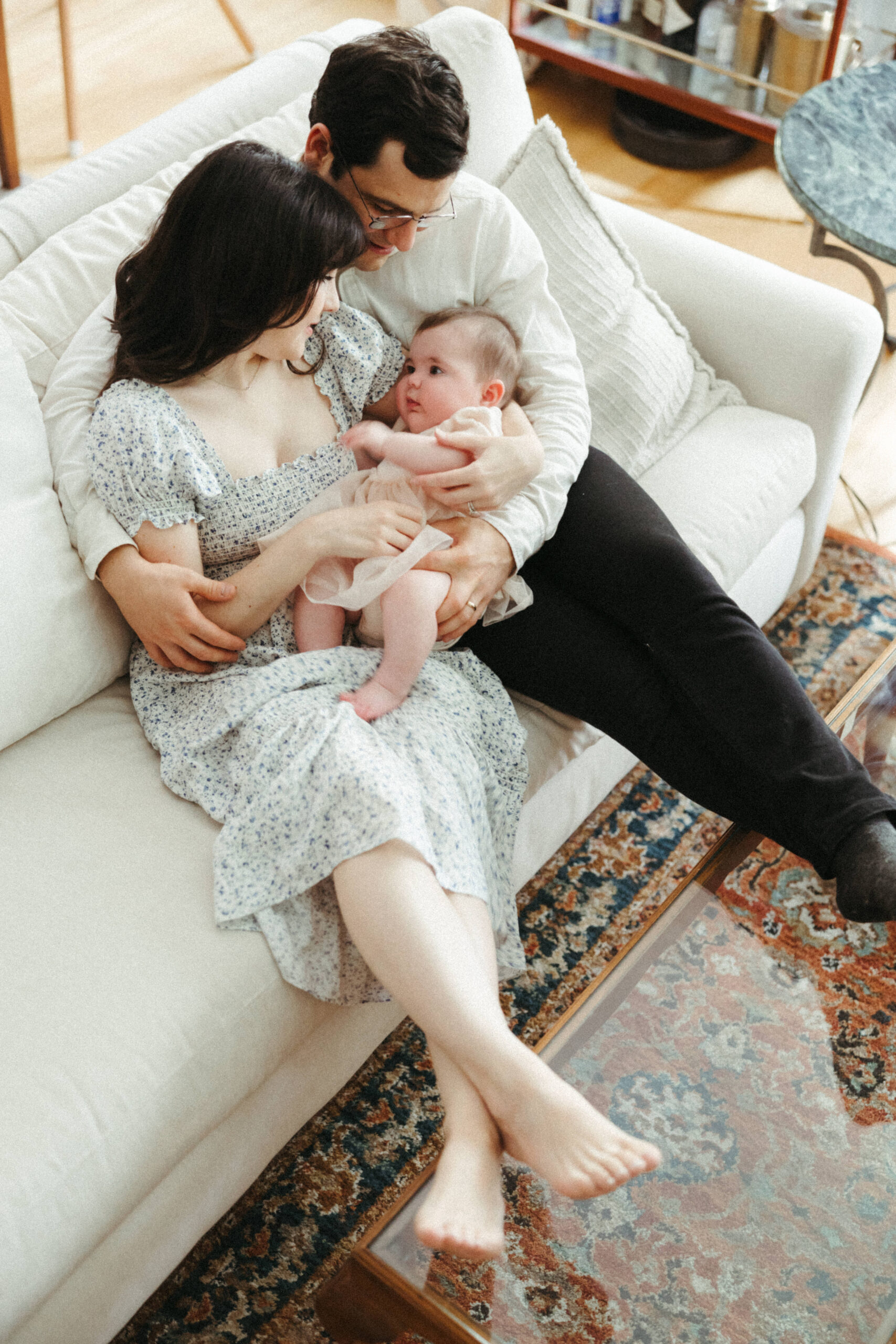 Beautiful infant with mom and dad in their modern in home family photo shoot