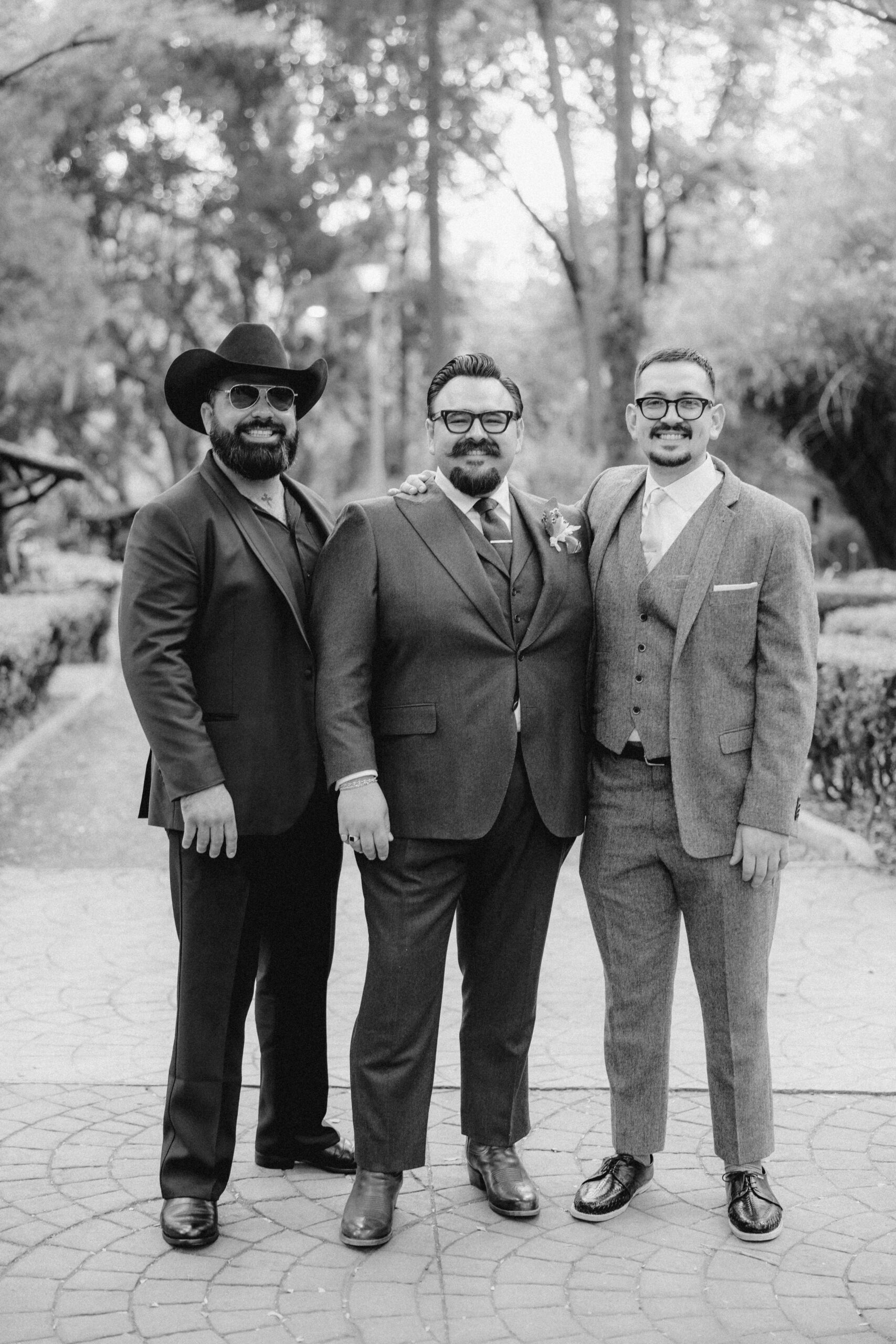 The groom poses with two of his groomsmen outside her Sobremesa wedding venue
