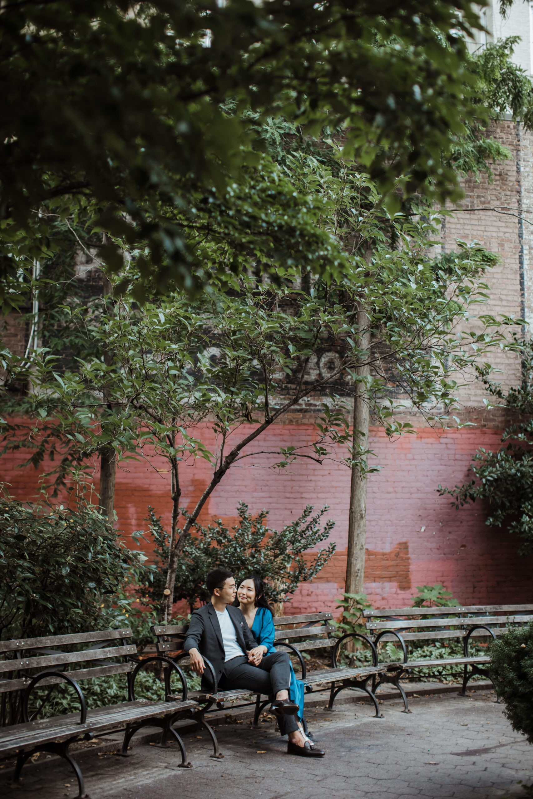 Beautiful couple sit on a New York park bench during their engagement photoshoot