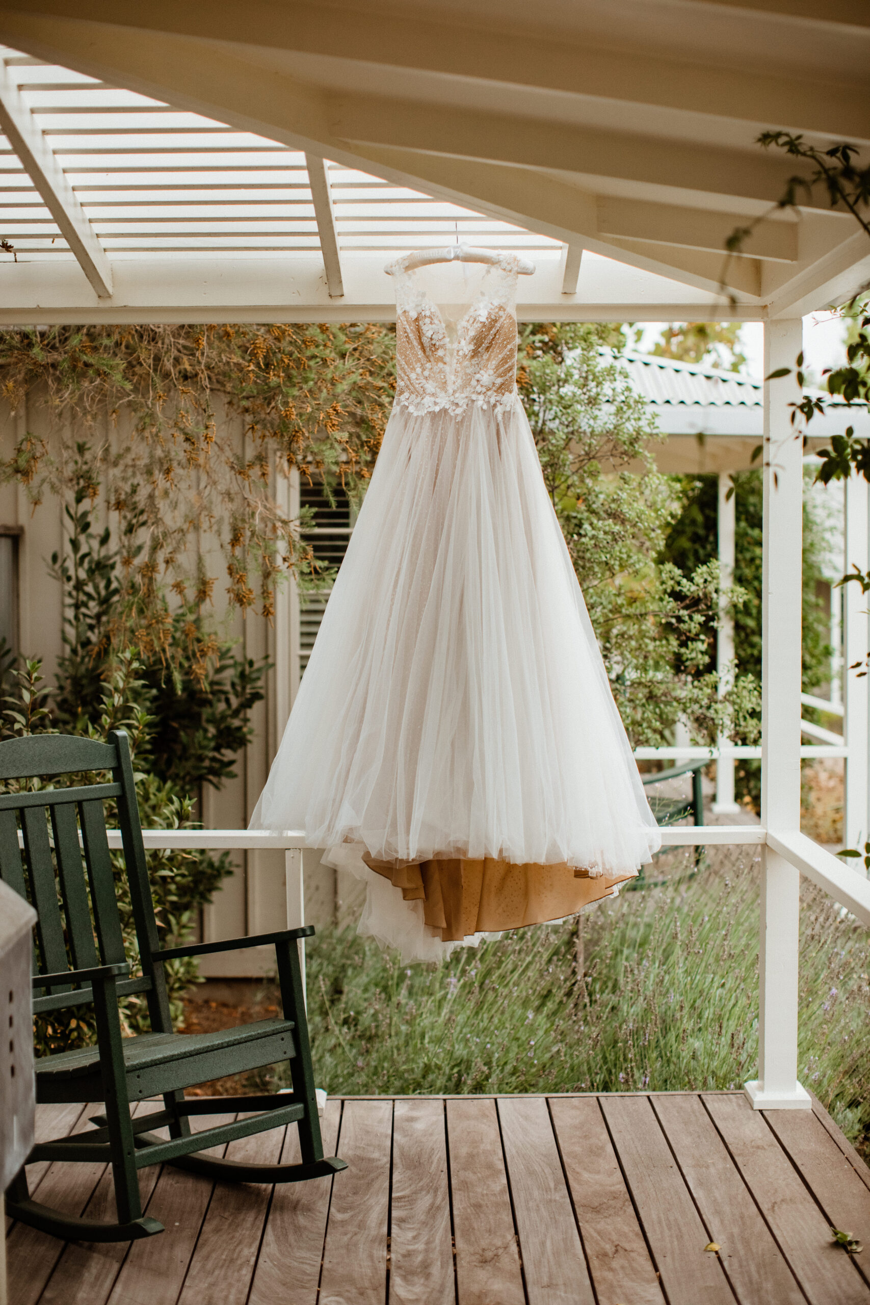 bride detail of dress hanging from ceiling at vineyard wedding venue. 