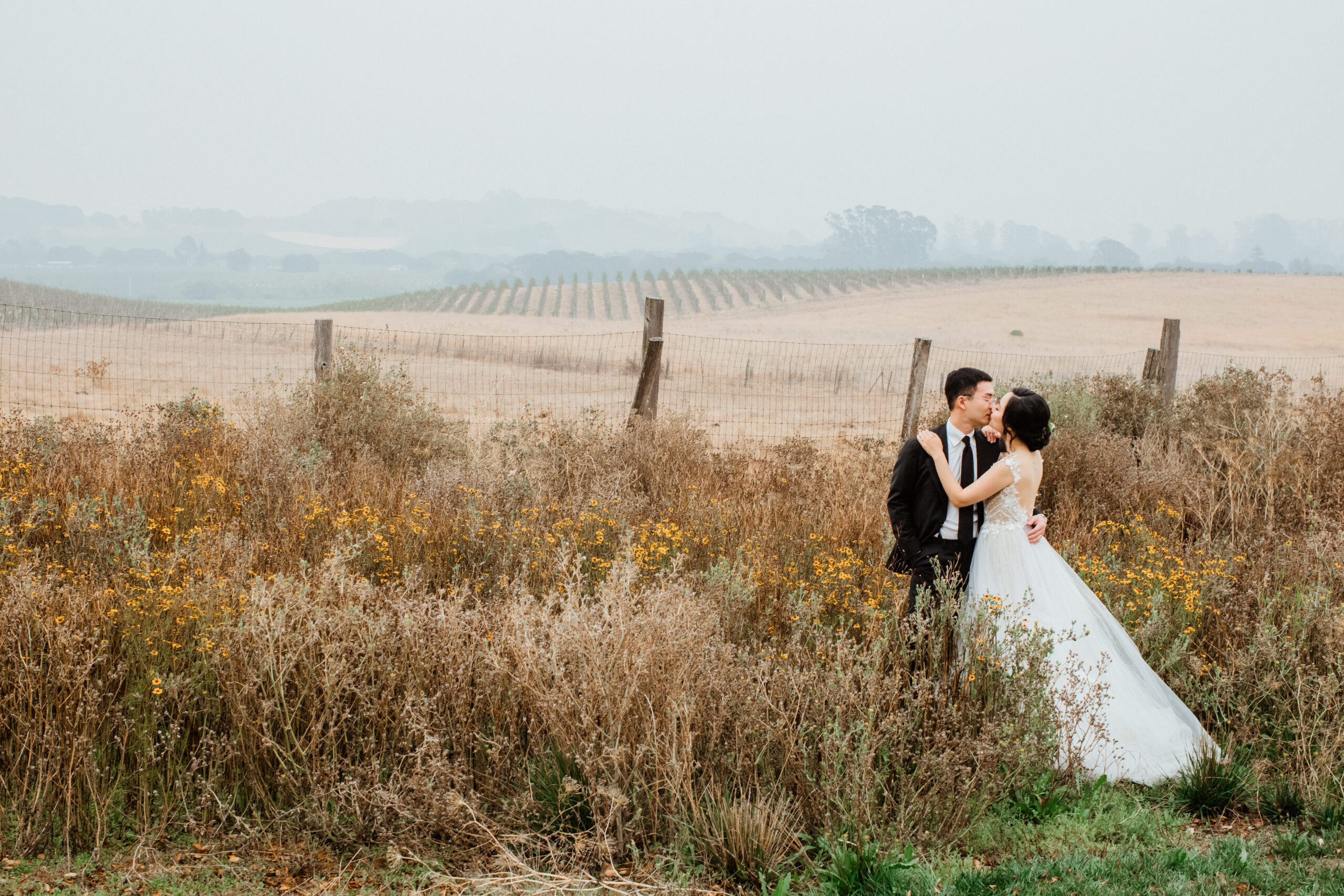 Beautiful bride and groom share a romantic moment overlooking the rows at their Napa valley vineyard wedding venue