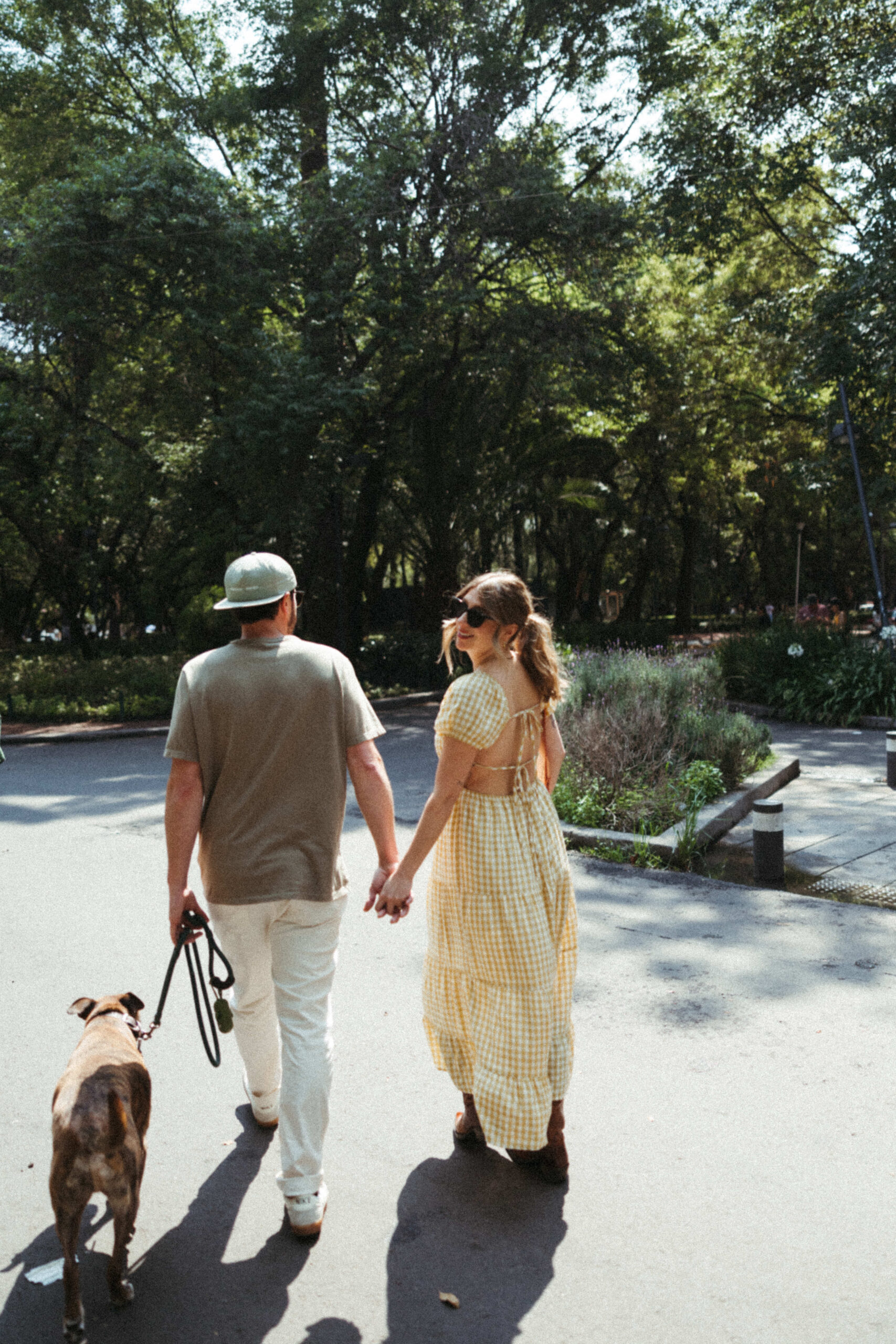 man and fiance walking in mexico city garden with their dog