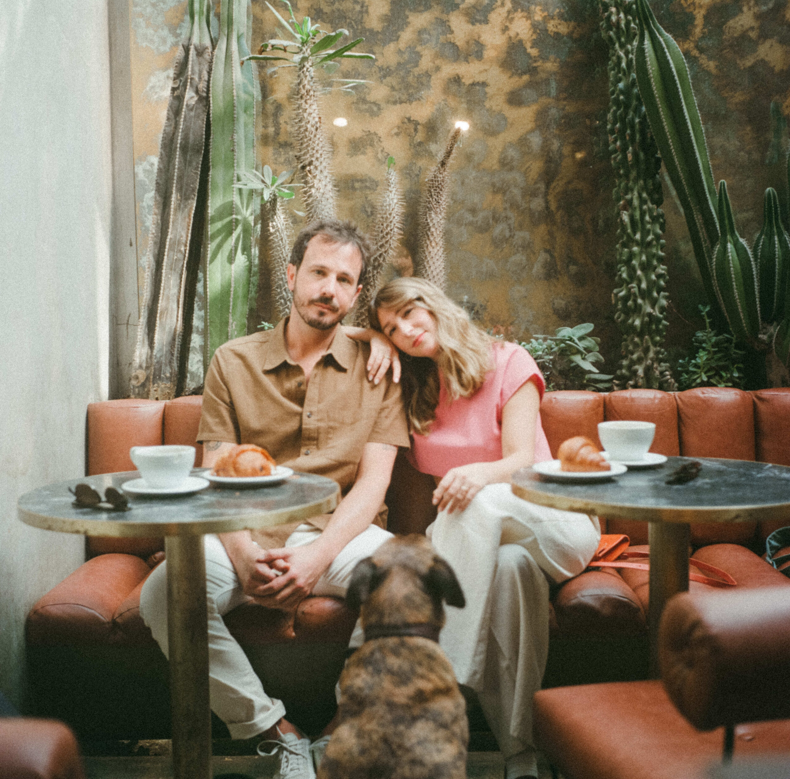 film photography with man and woman eating croissants while their dog is looking at them