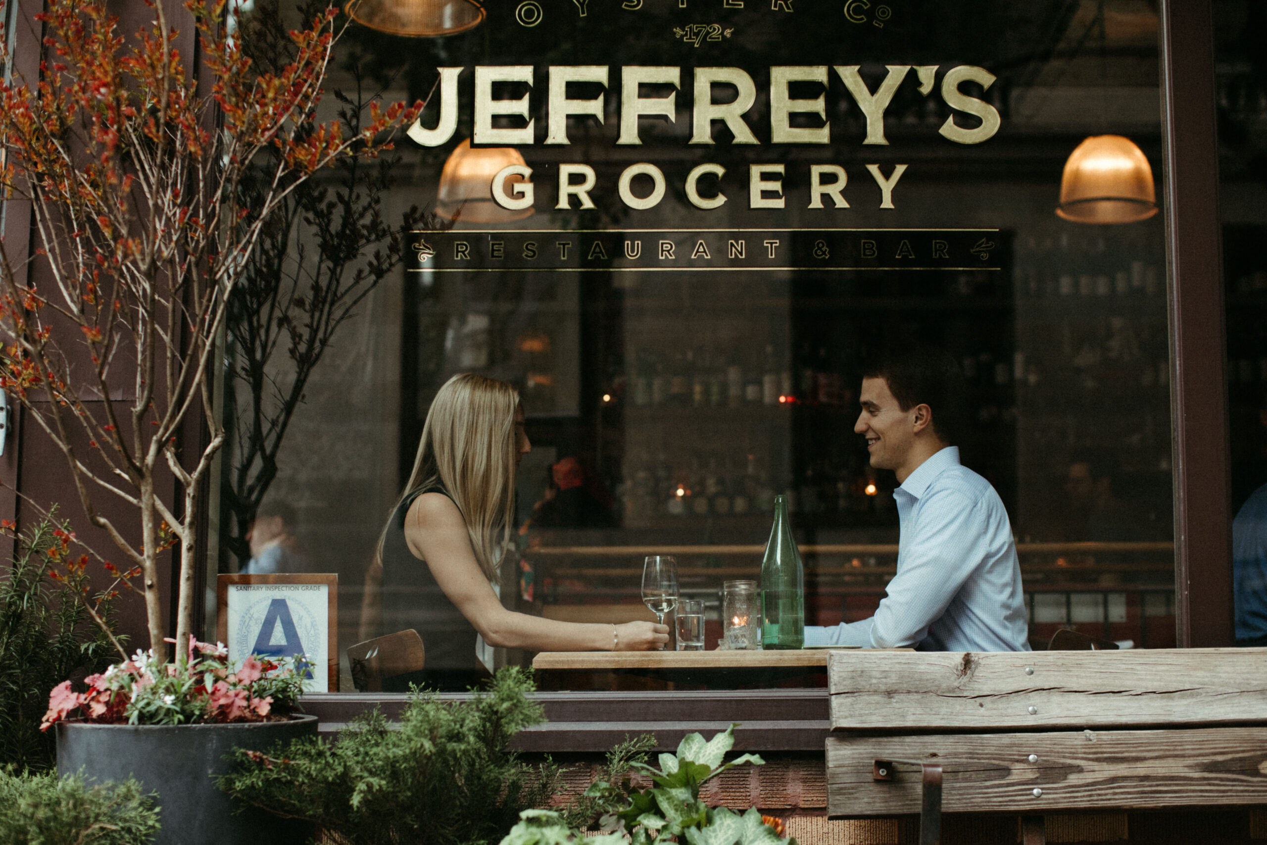 Stunning couple share wine and smiles at Jeffrys in the West Village during their New York engagement photoshoot