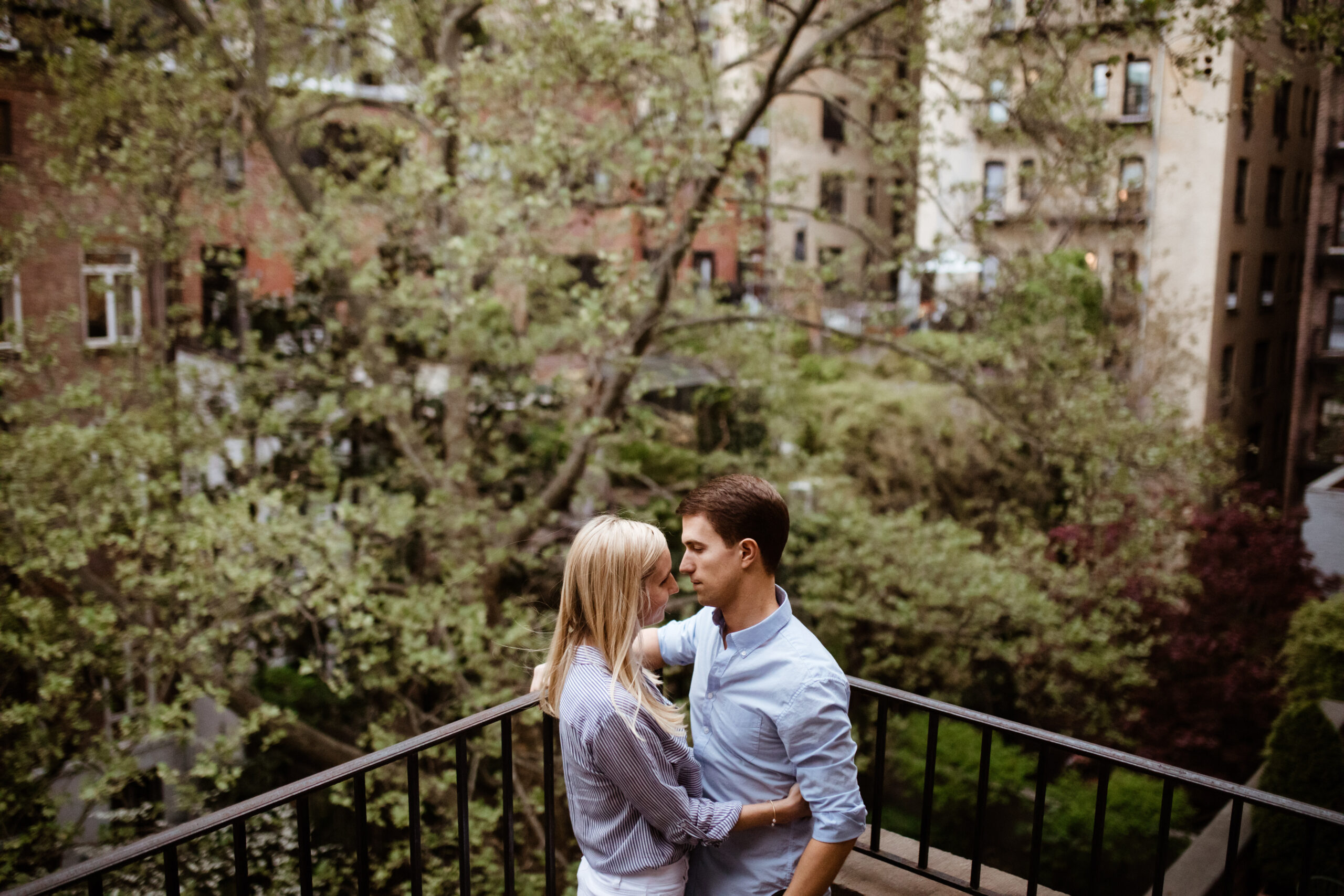 Stunning couple pose on a patio with with a tree during their outdoor engagement photos in West Village New York! 