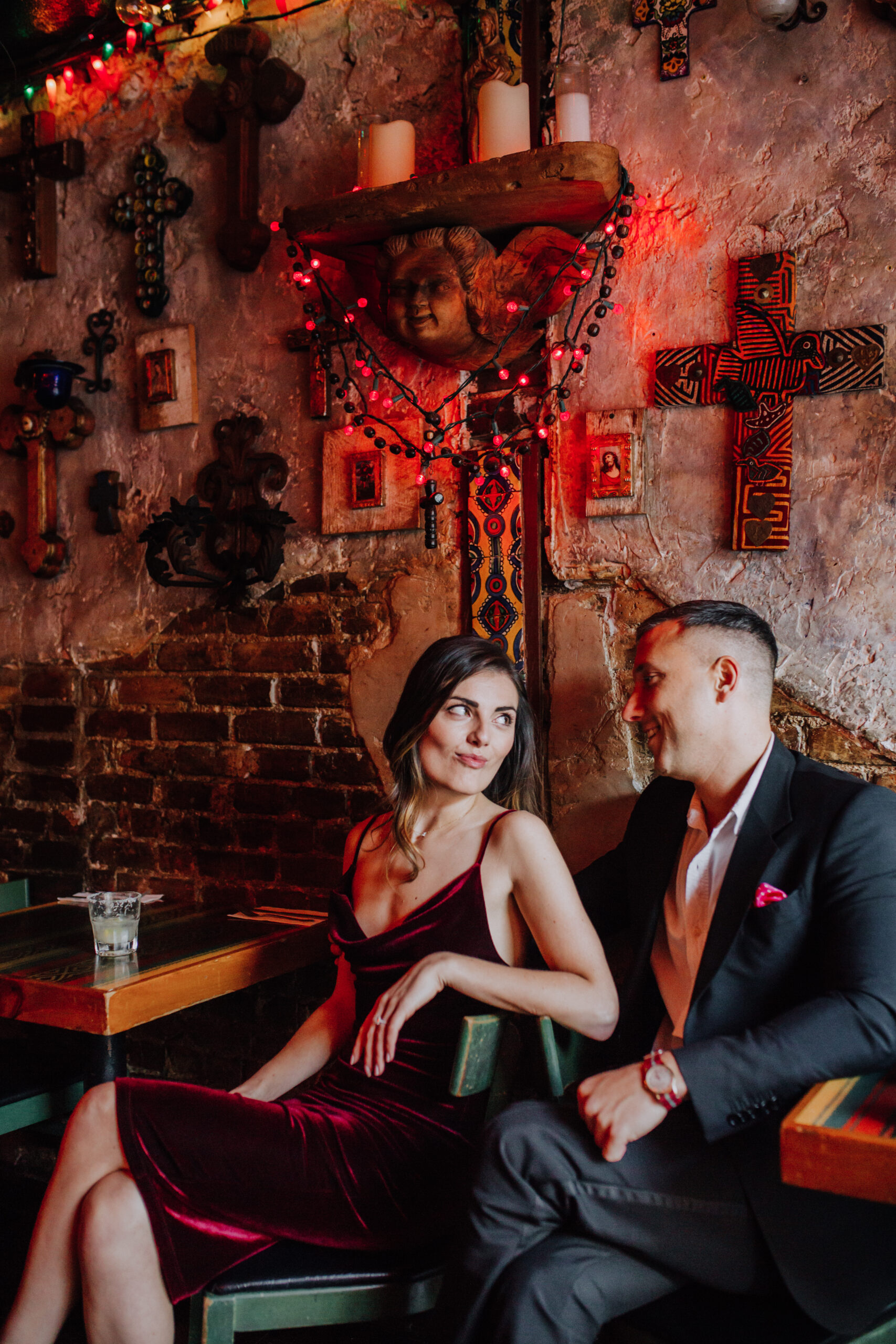 Stunning couple sit in front a cross covered wall in during their dreamy NYC engagement photos