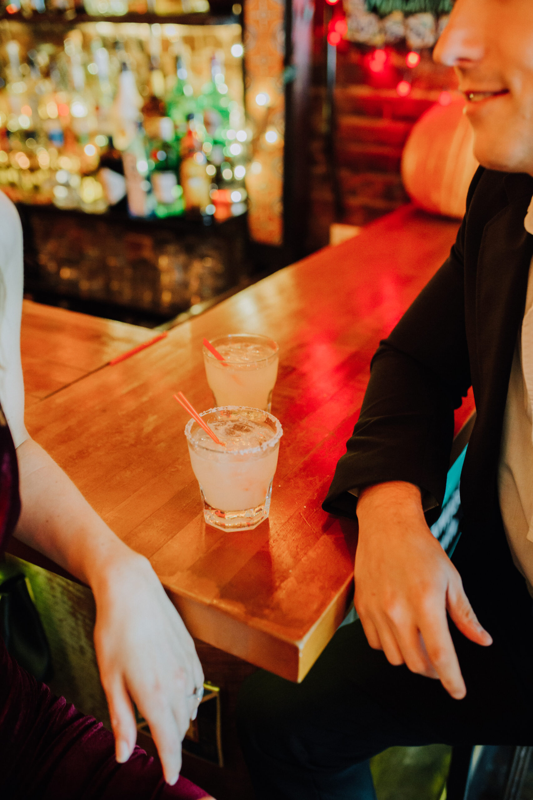 A stunning couple share some drinks during their bar engagement photoshoot