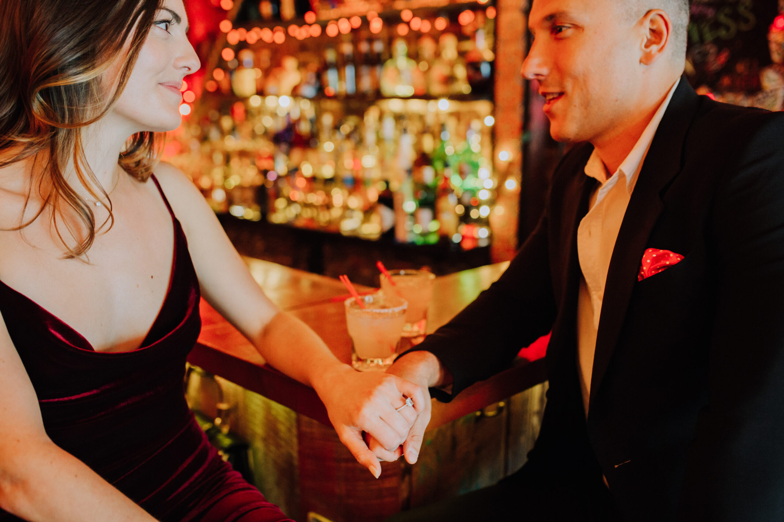 couple holds hands during their dreamy bar engagement shoot