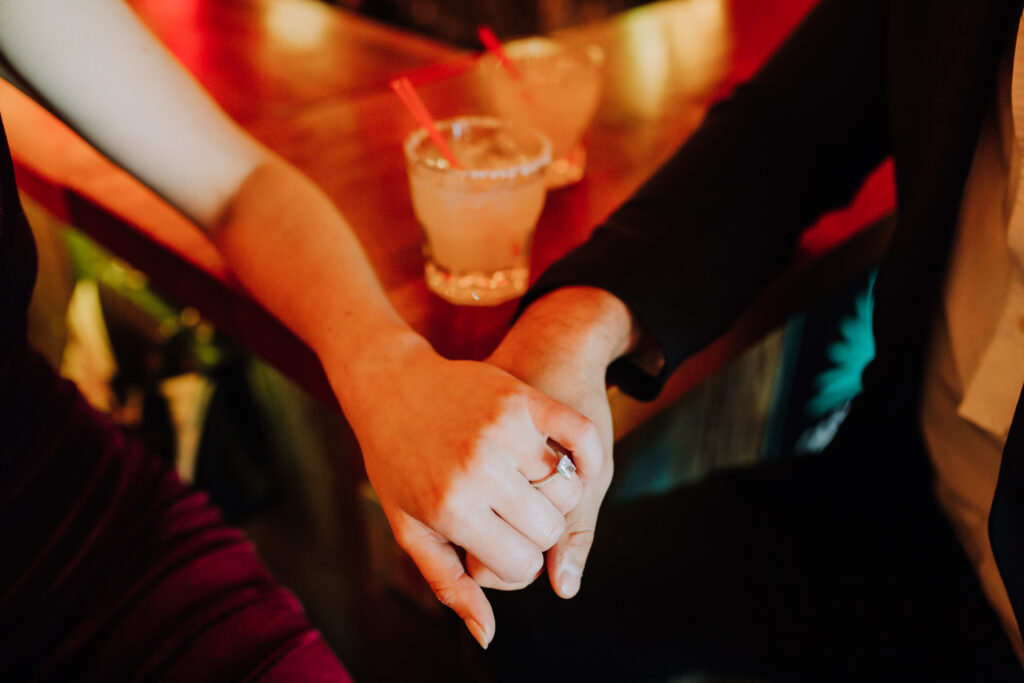 couple holds hands across the bar during their dreamy NYC engagement shoot