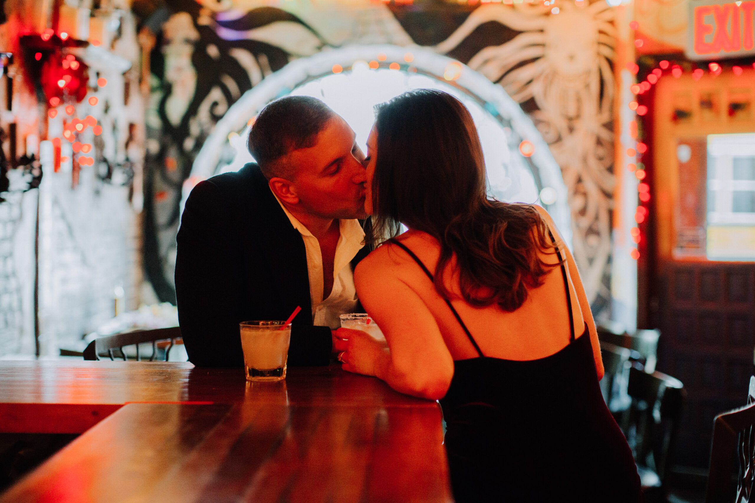 stunning couple share a kiss over drinks in a bar