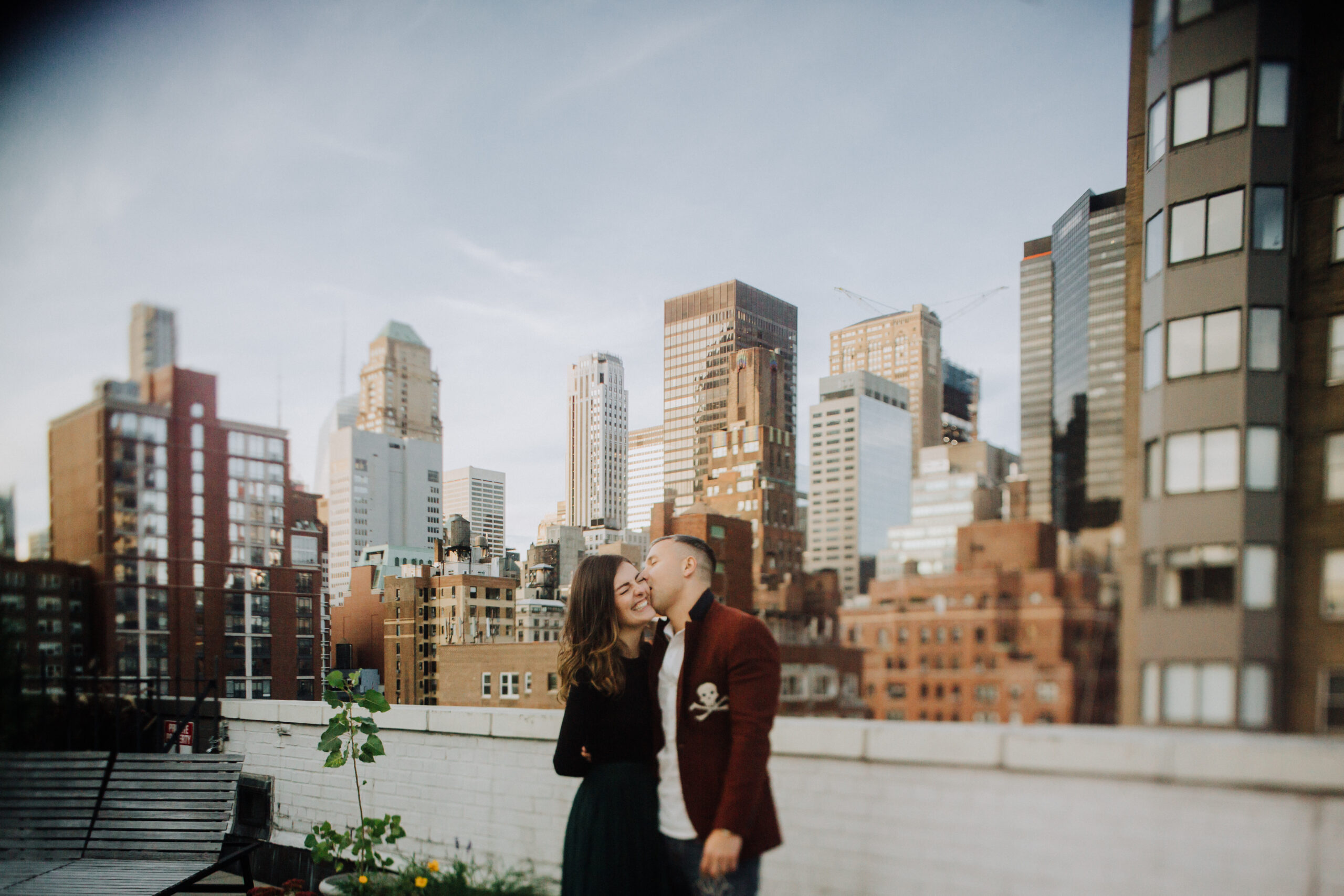 couples kissing on rooftop deck overlooking the new york city skyline. 