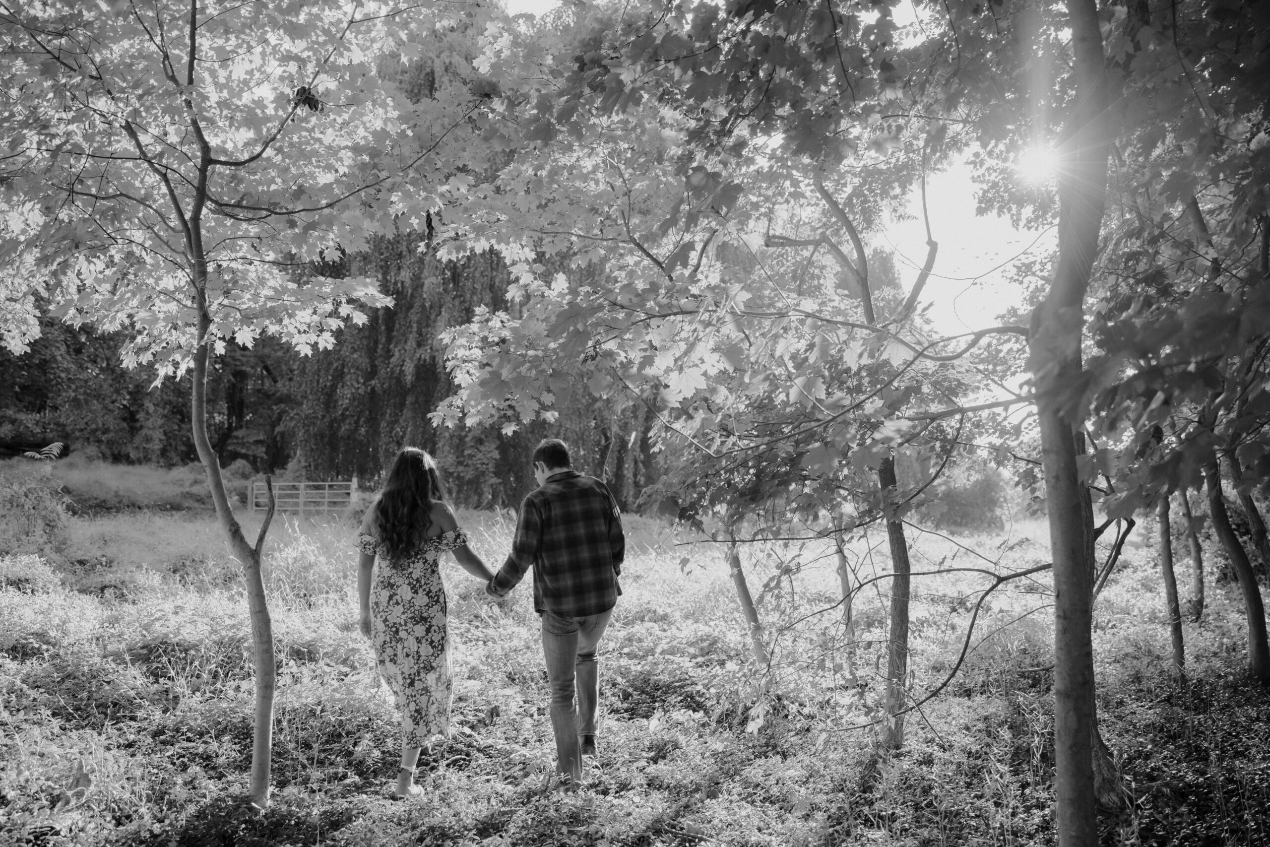 Stunning couple walk in nature holding hands during their casual engagement photo shoot