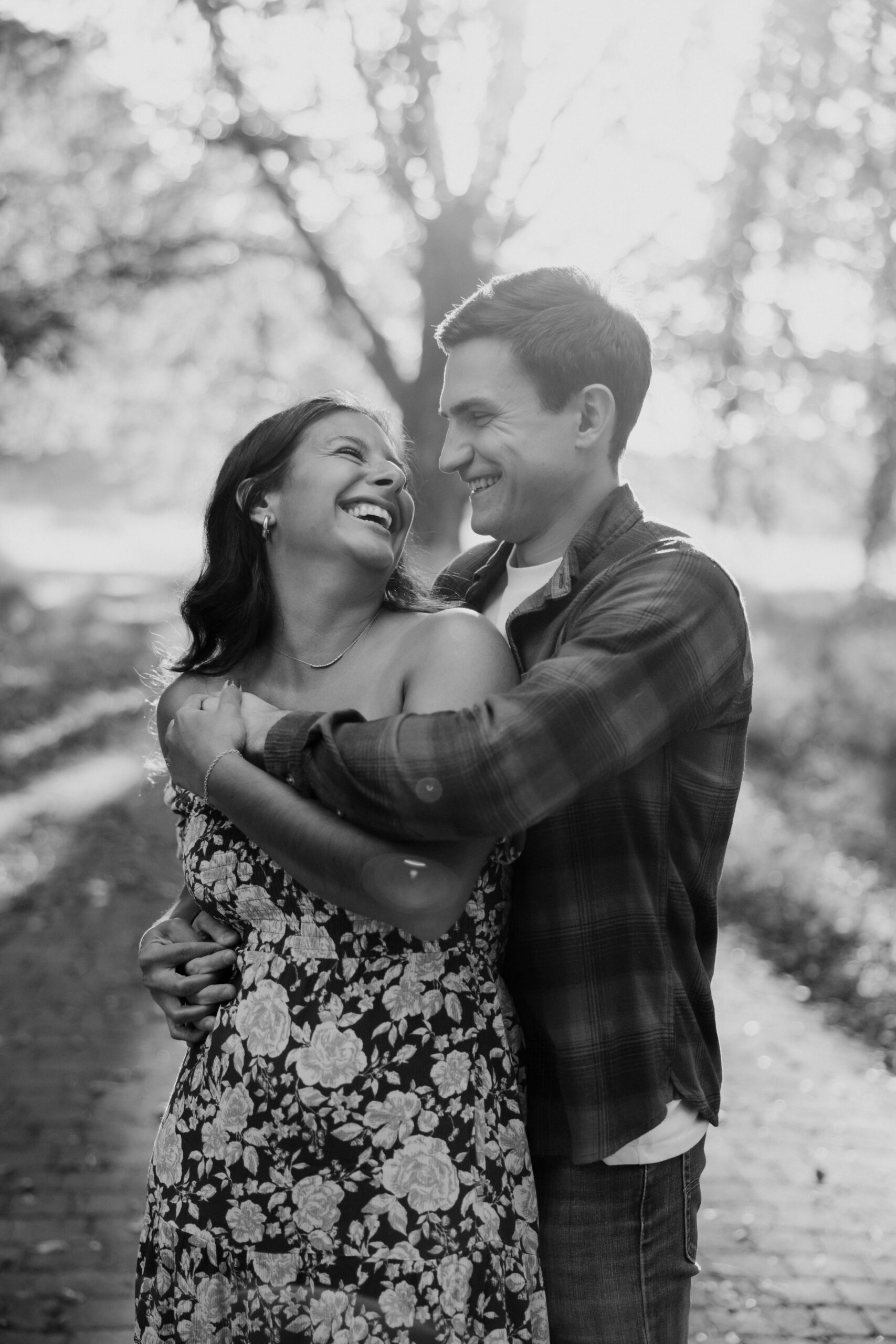 Beautiful couple hug under the trees during their casual engagement photos