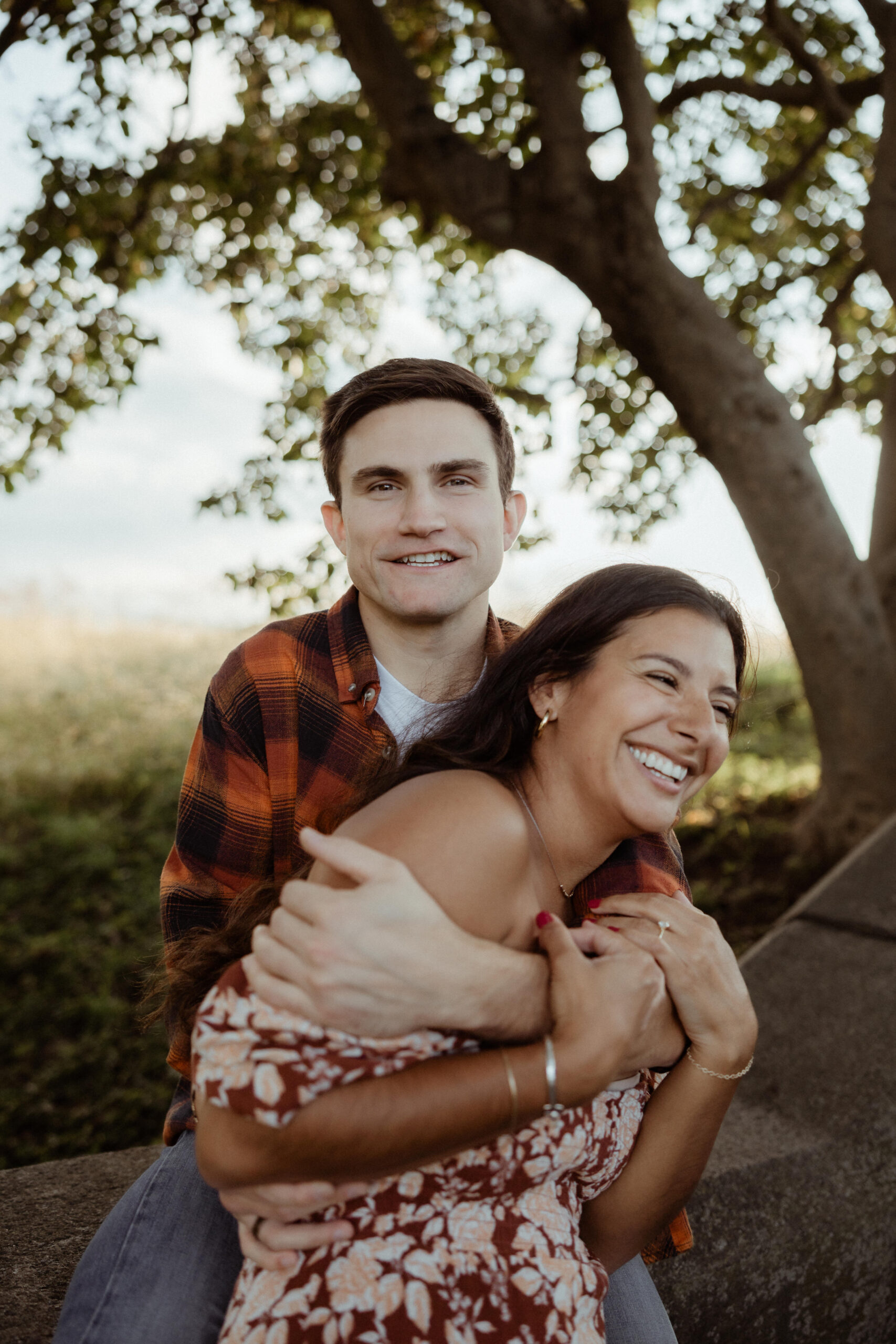 Couple embrace each other in the field during their casual engagement photo shoot