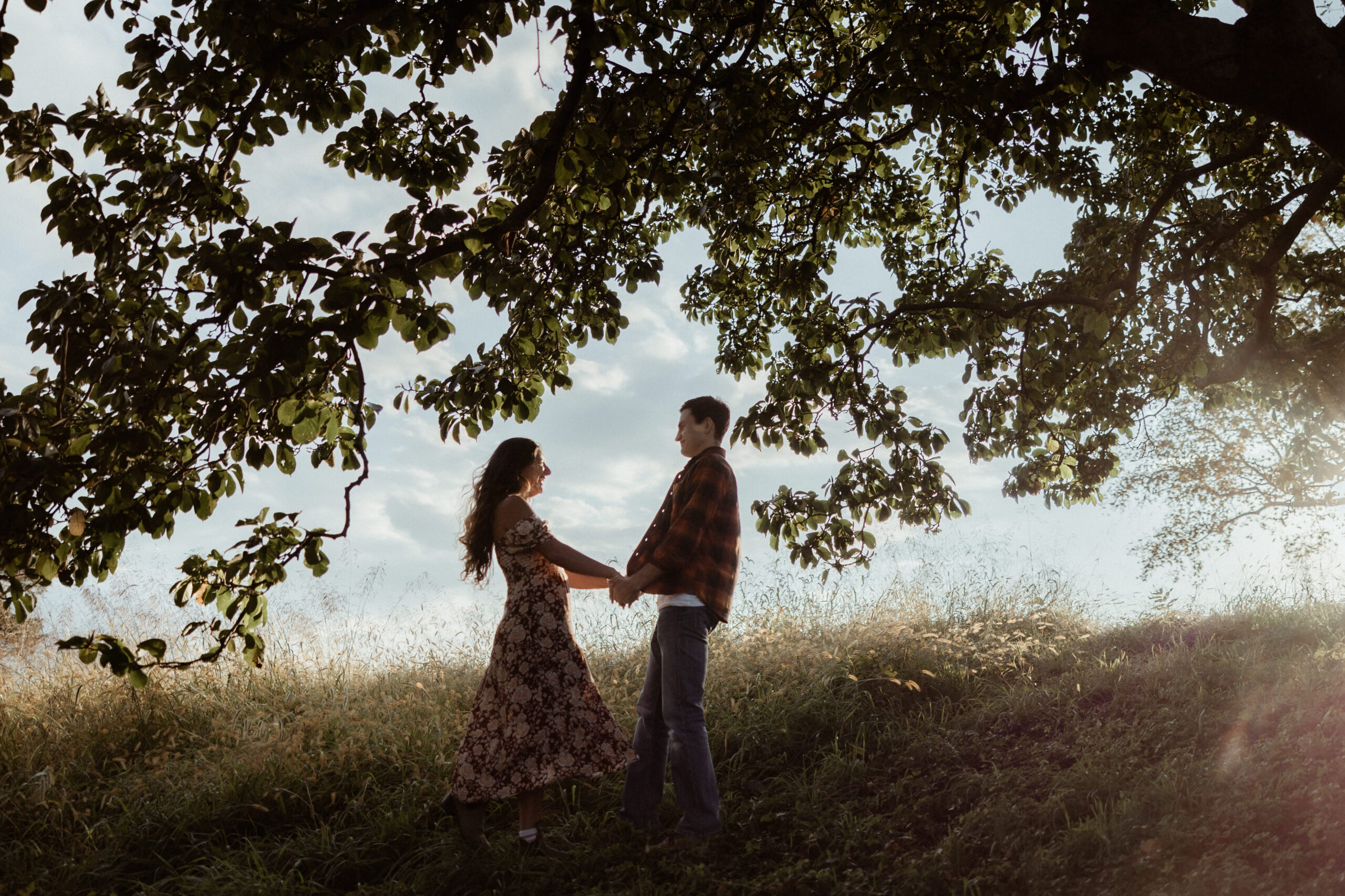 Beautiful couple embrace under the trees during their casual engagement photos