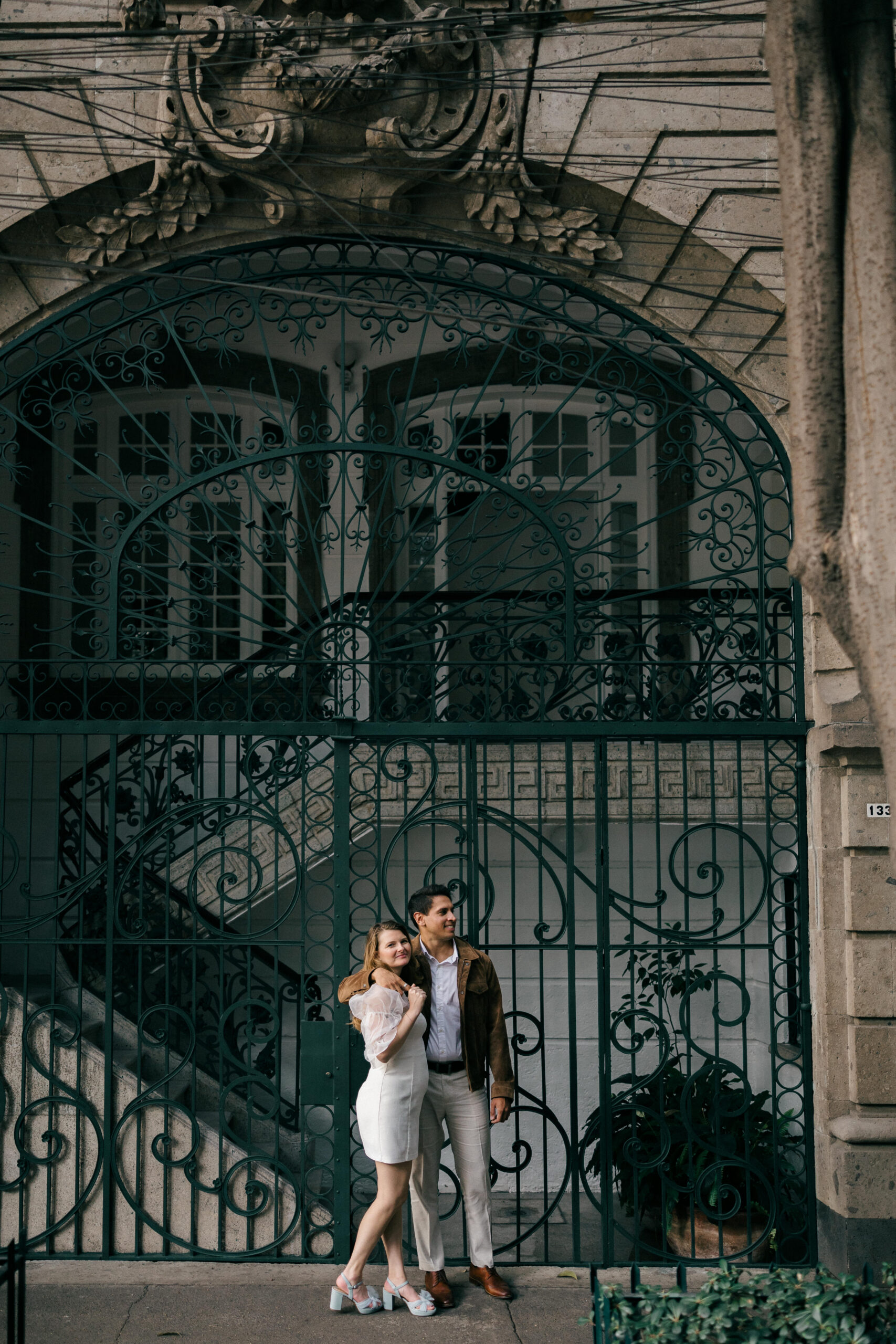 Dreamy couple pose together in front of wrought iron gate 