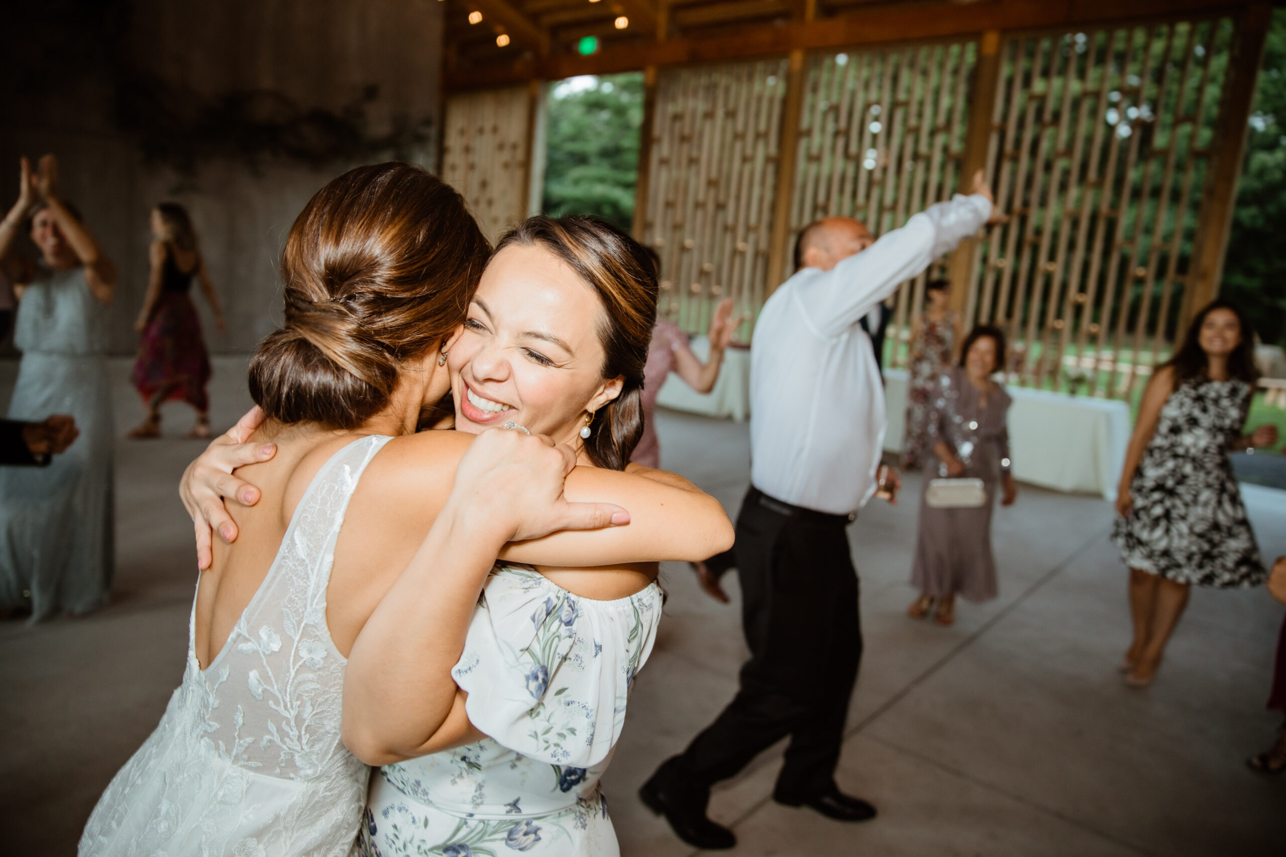 Beautiful bride and mom share a hug in front of guests during their modern Gather Greene wedding in Upstate New York