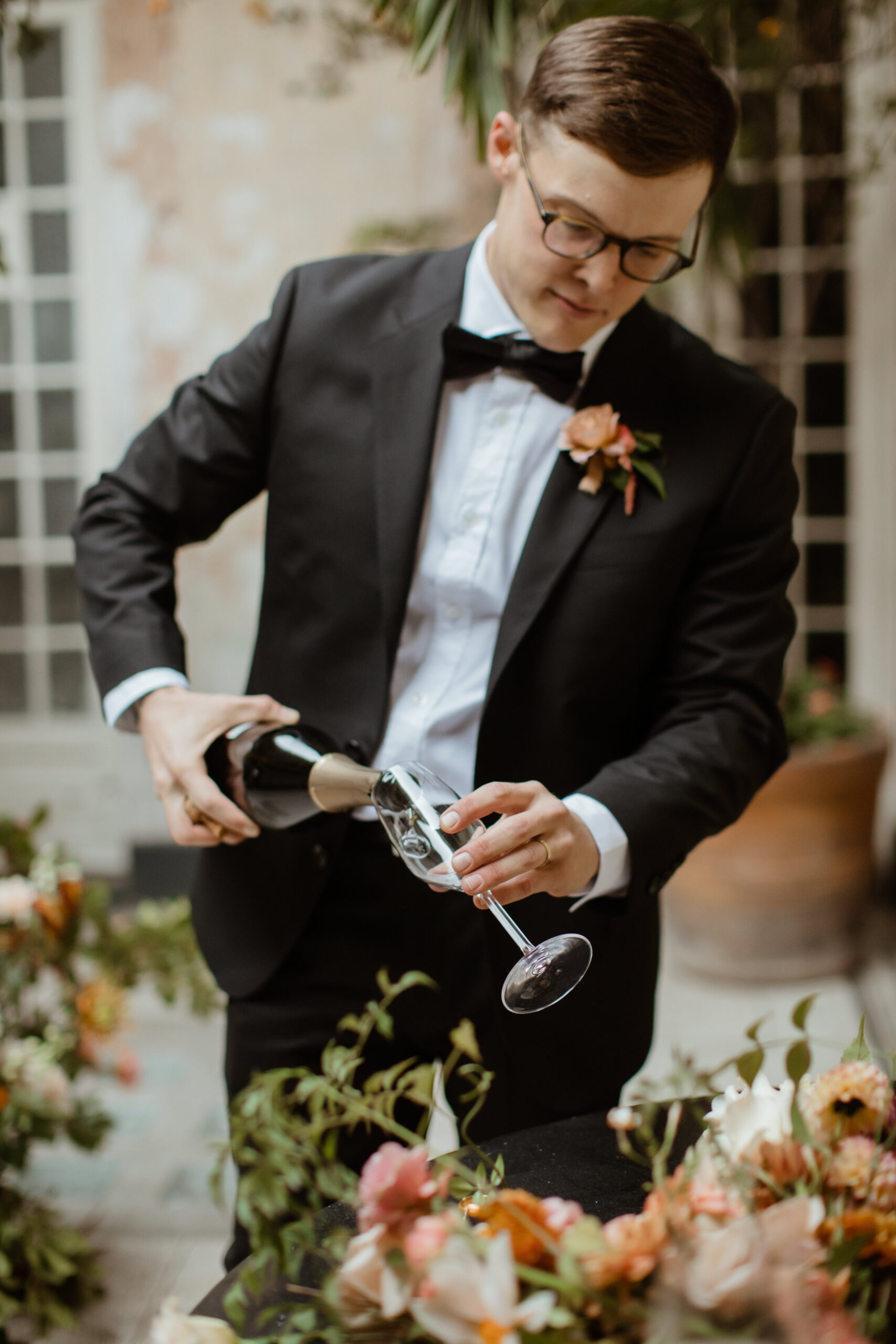 Handsome groom pours his new wife a glass of champagne to celebrate their dreamy elopement