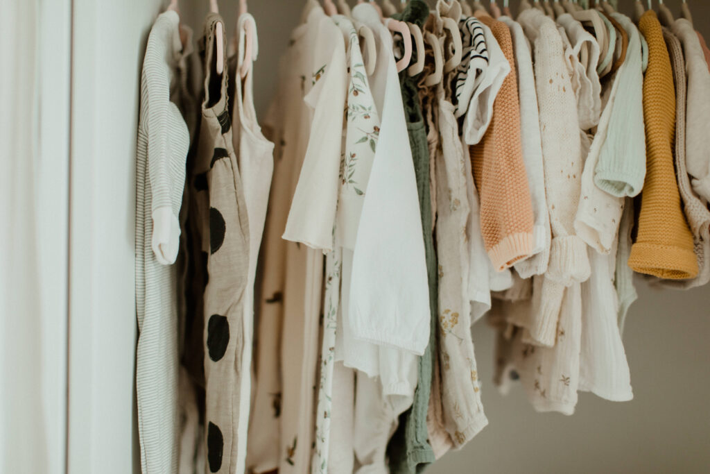 Neutral baby clothes hanging in a closet during at at home newborn portrait session
