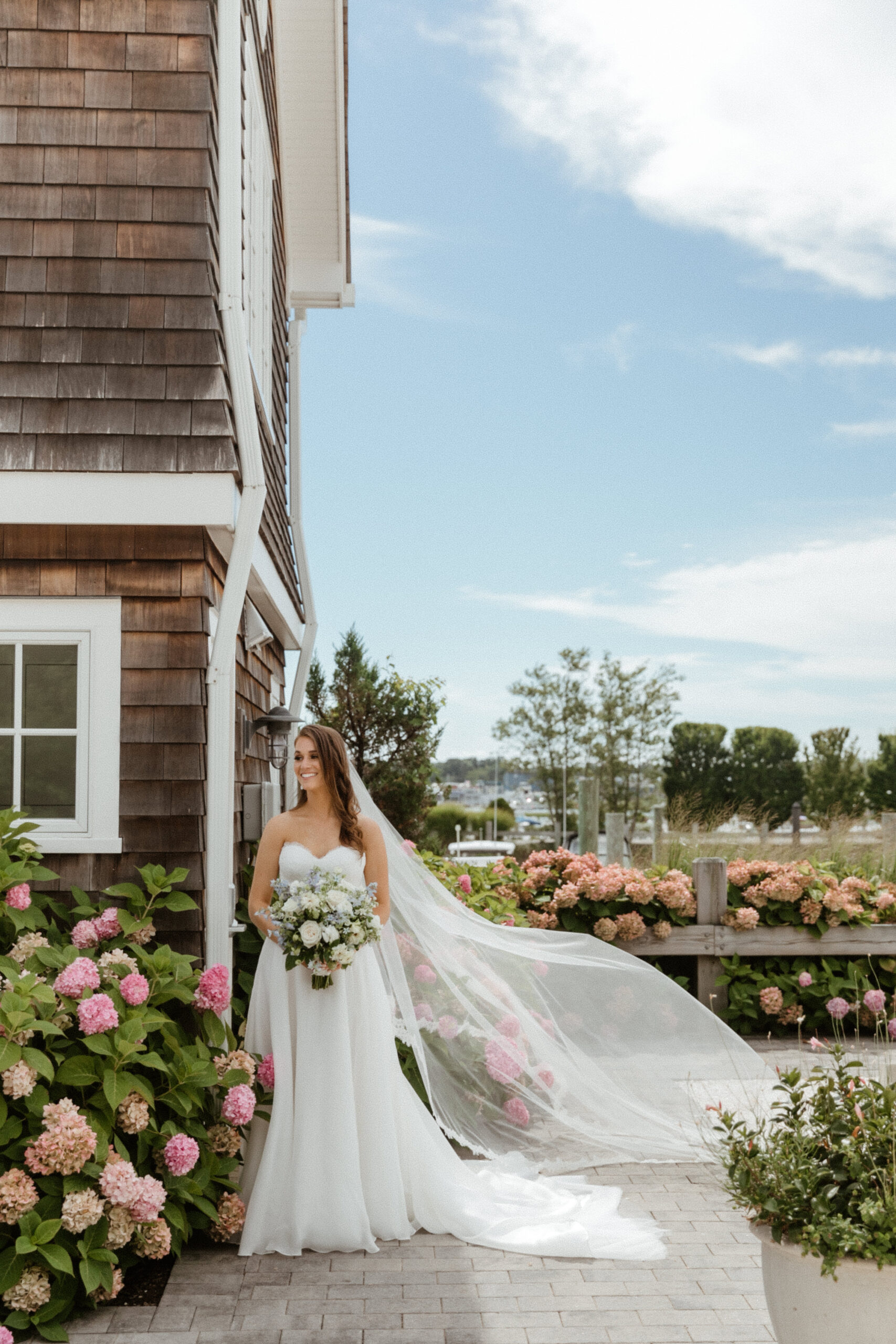 bride poses outside her north east beach wedding venue with the stunning pink flowers