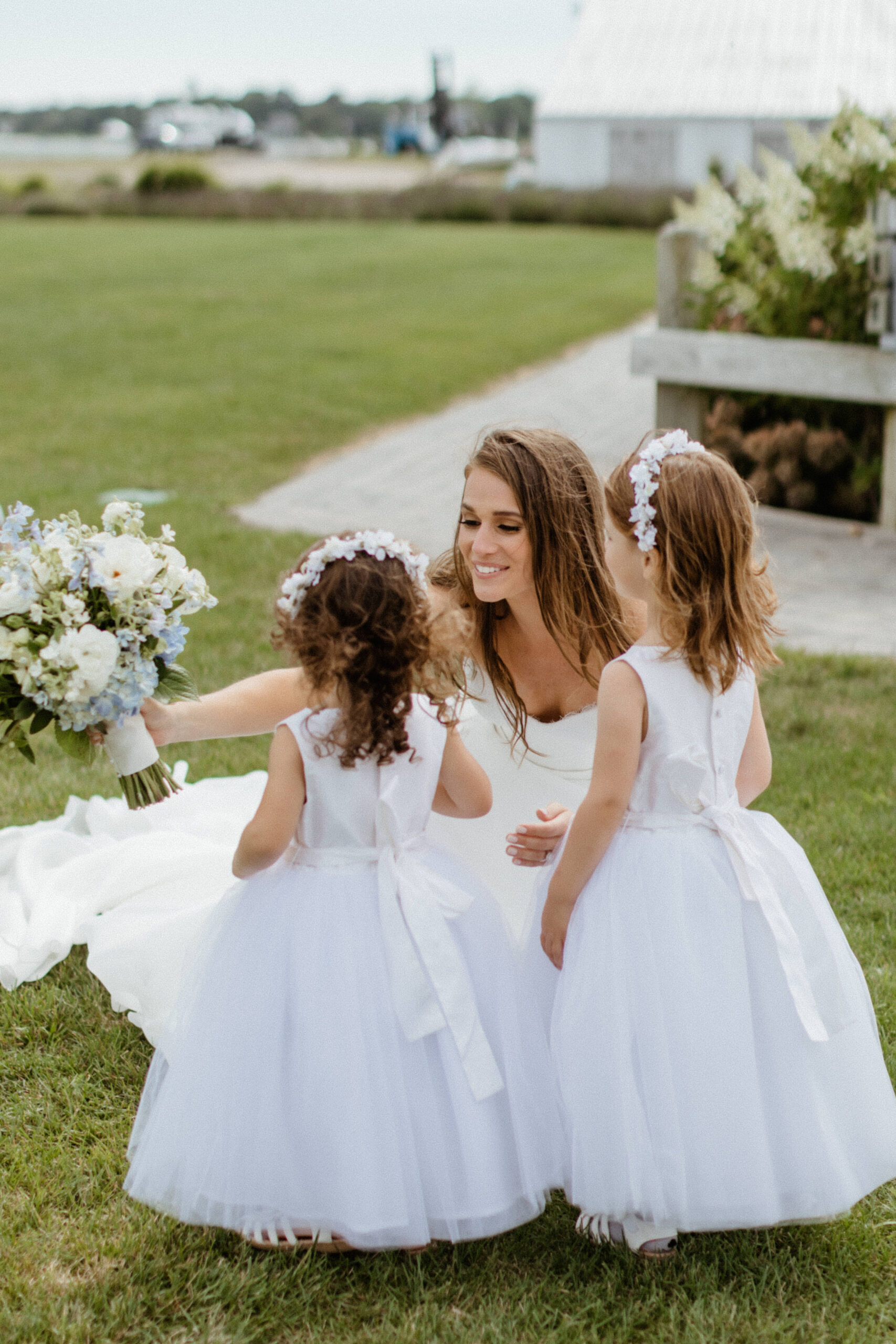 bride greets and hugs the flower girls for her dreamy north east beach wedding