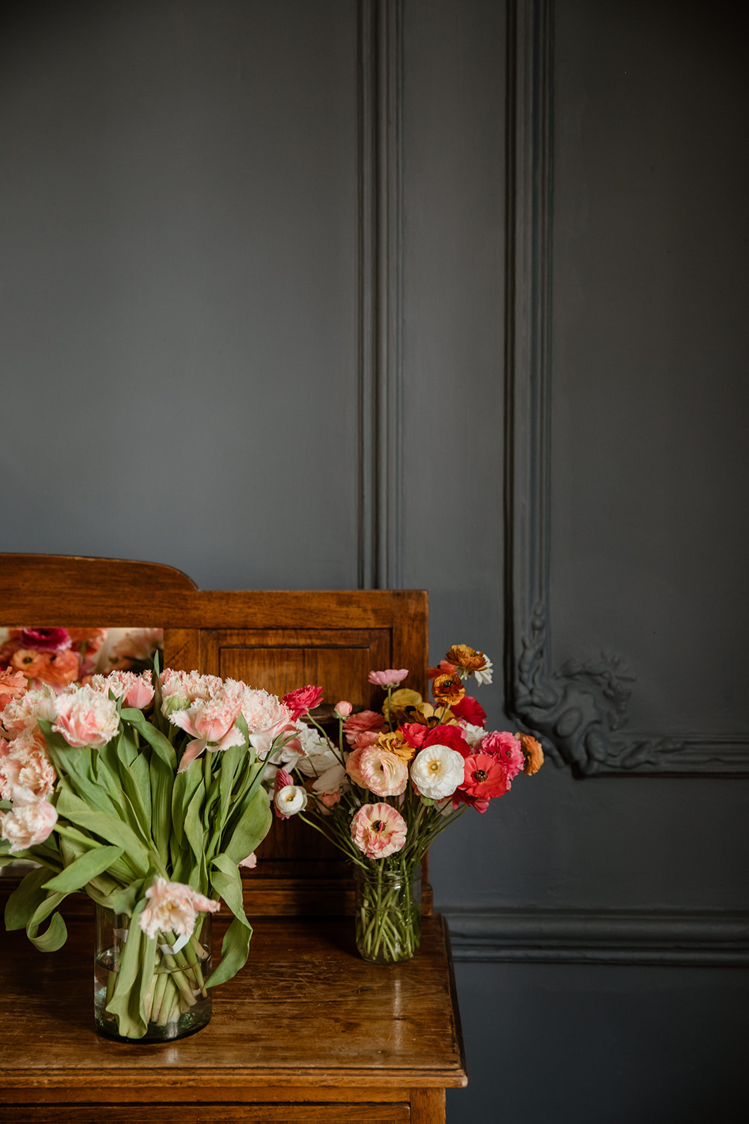 Wedding florals sit strikingly against a grey wall 