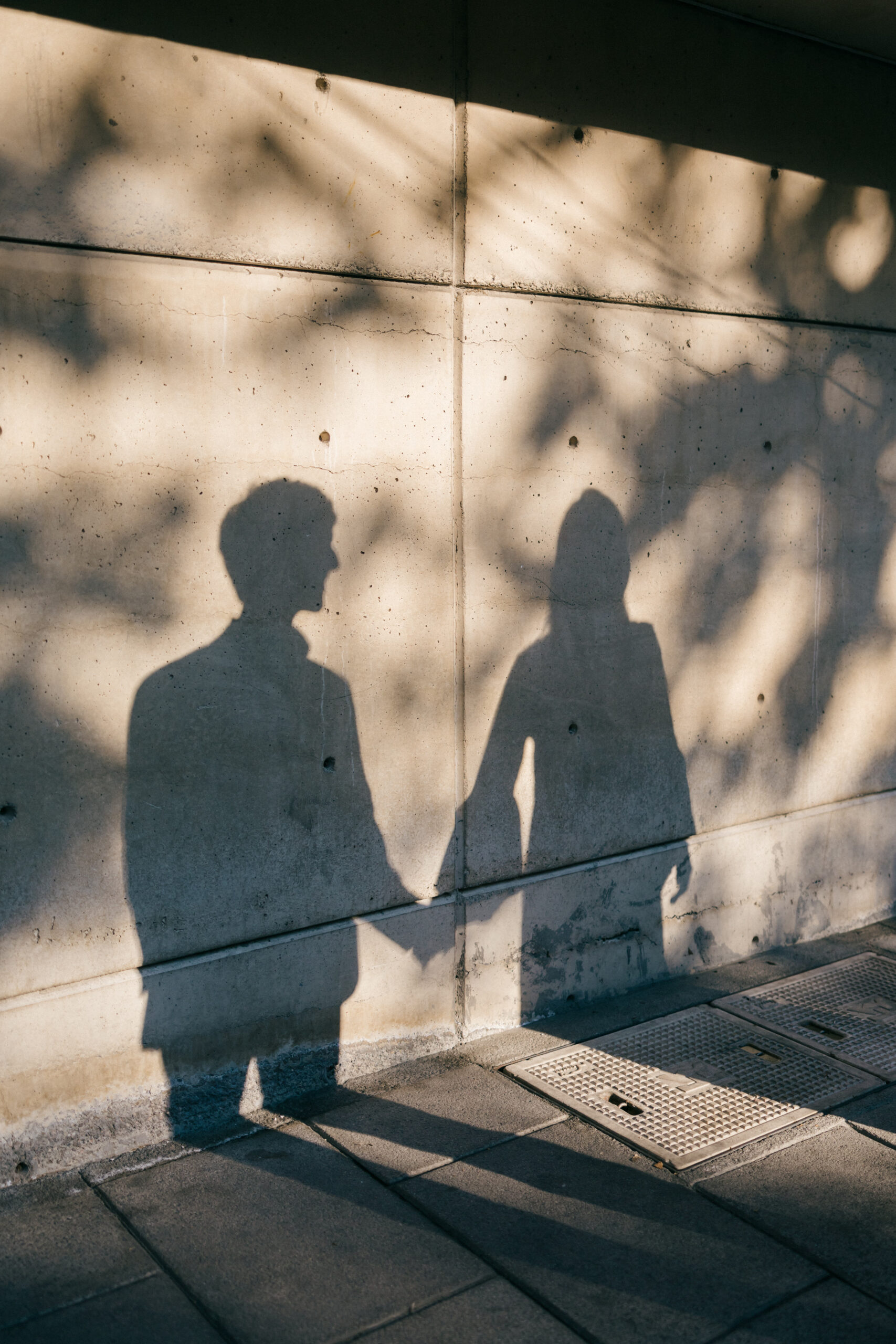 Couple holding hands as their shadow prints on the foot of the building