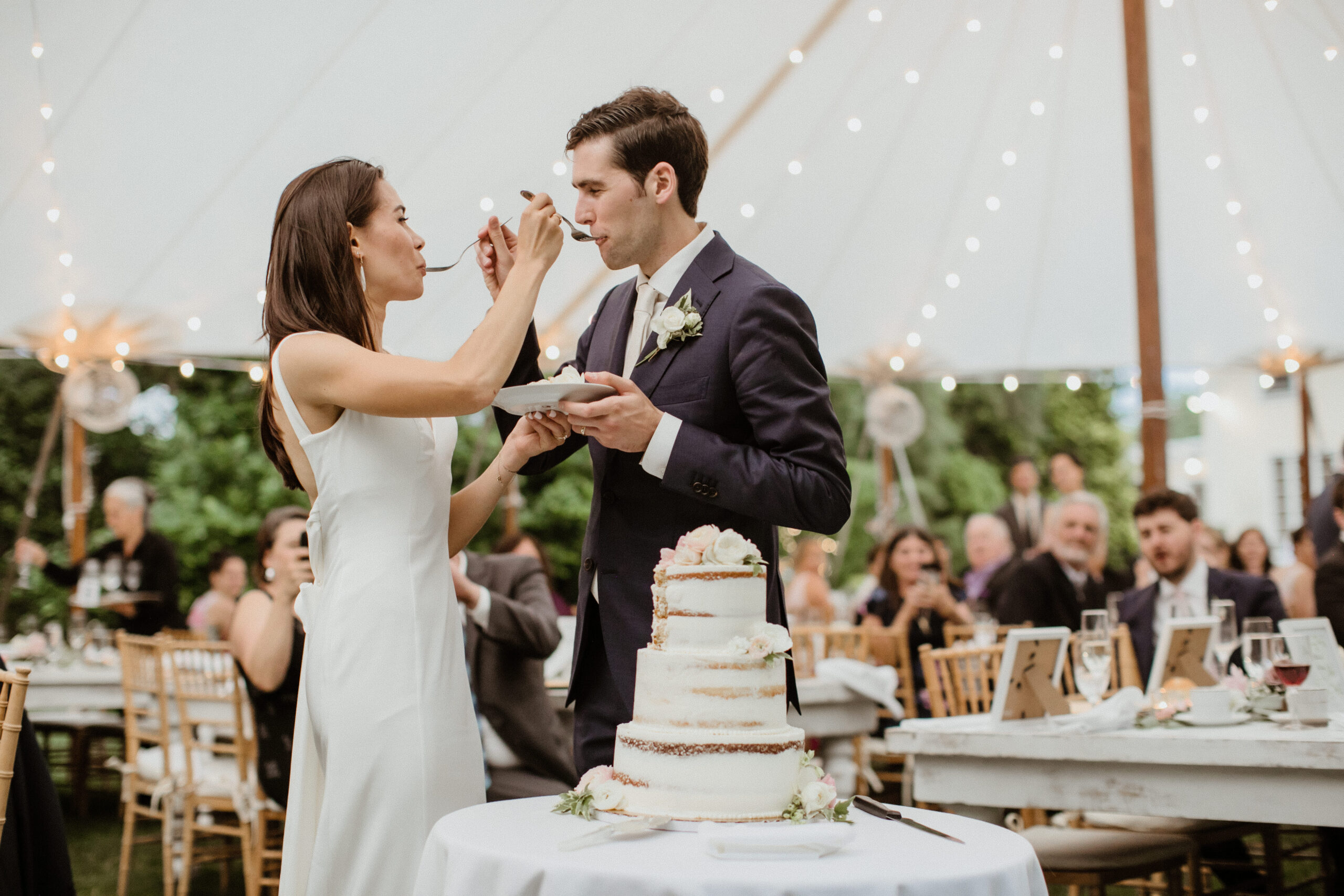 Stunning bride and groom feed each other cake during their stunning Long Island Wedding