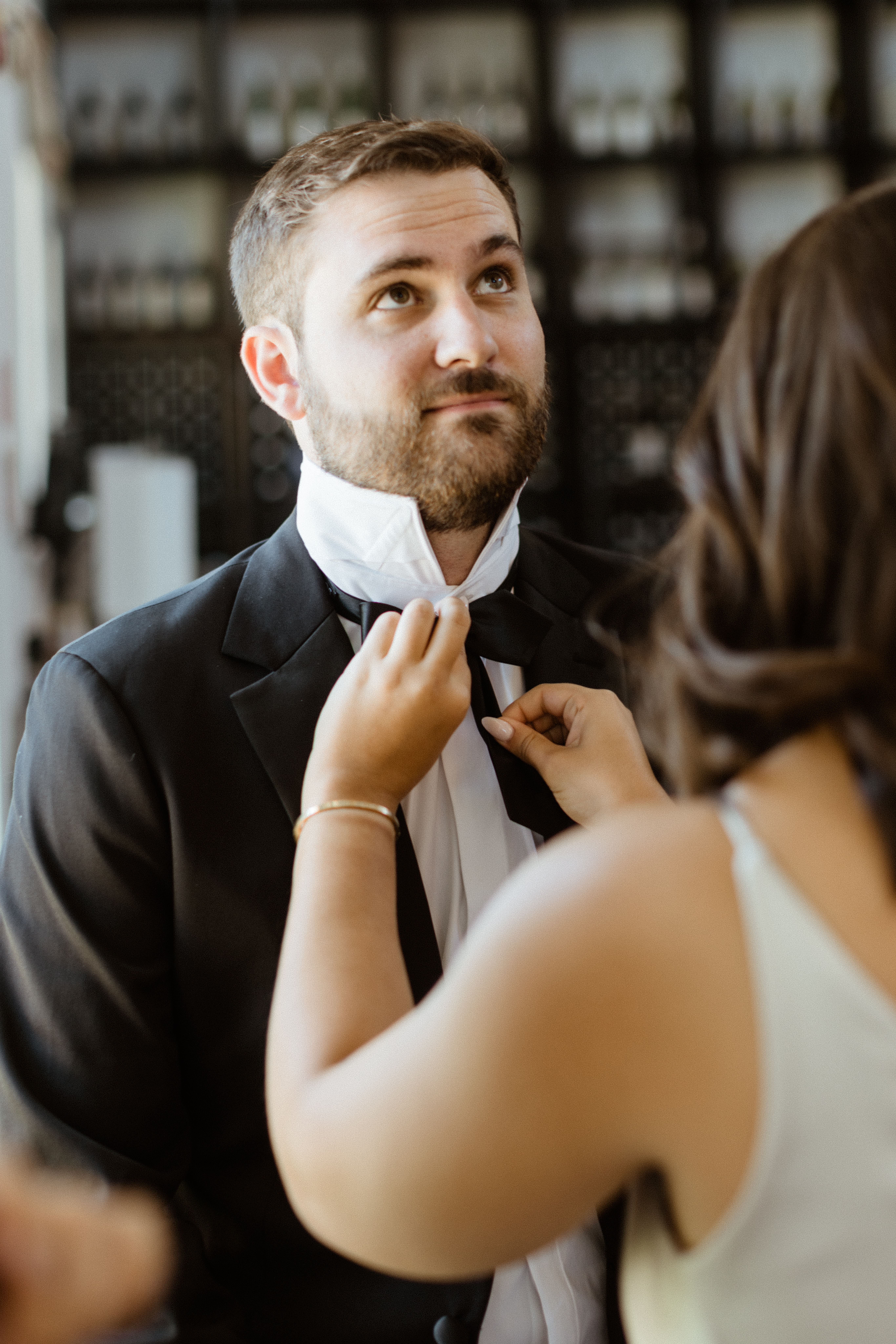 Groom gets help tying his bowtie before his dreamy Bedell Winery wedding
